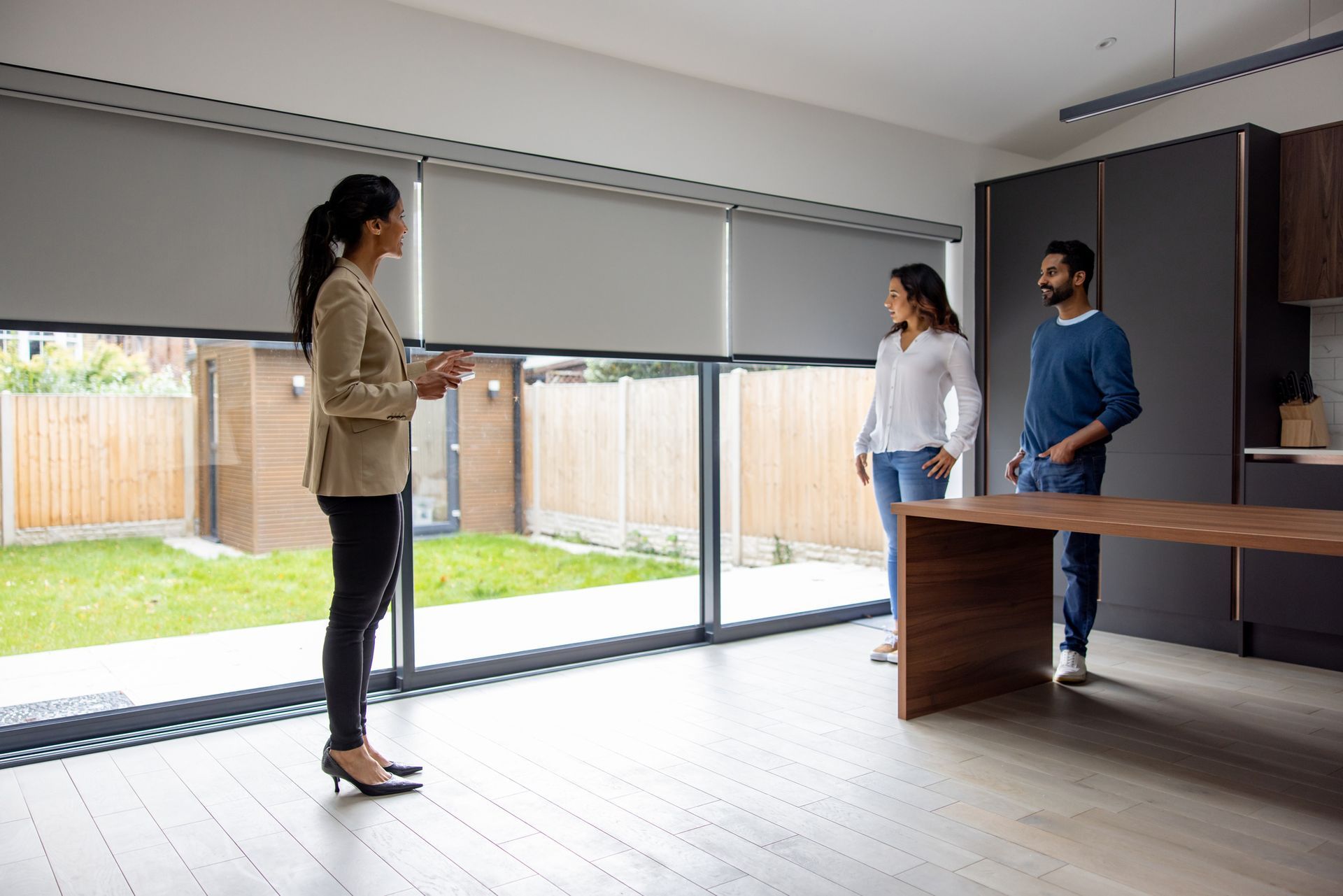 A real estate agent is using a remote control to lower a house’s motorized window treatments. A real estate agent is using a remote control to lower a house’s motorized window treatments.