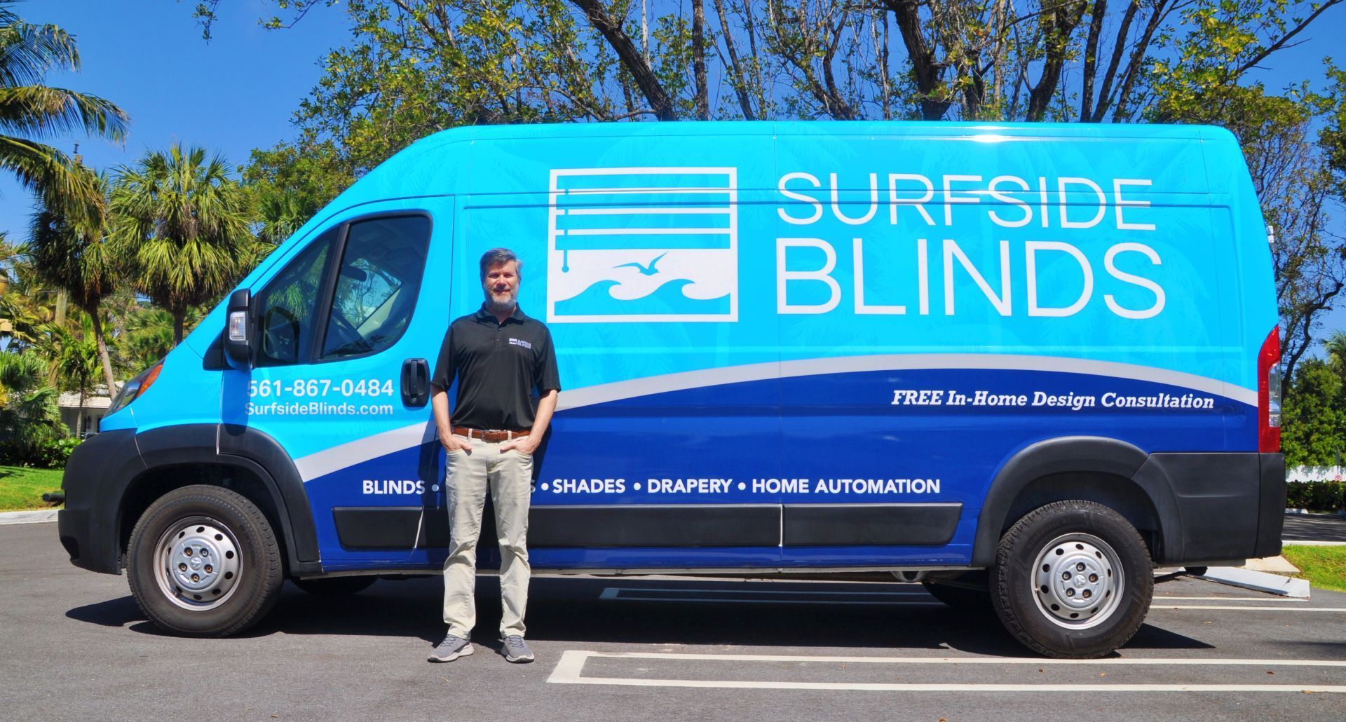 Blue Surfside Blinds van with a man standing beside it in a sunny parking lot.