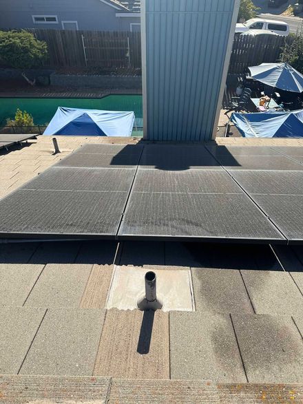 Roof view with a central vent pipe, asphalt shingles, and a backyard below with blue canopy tents.