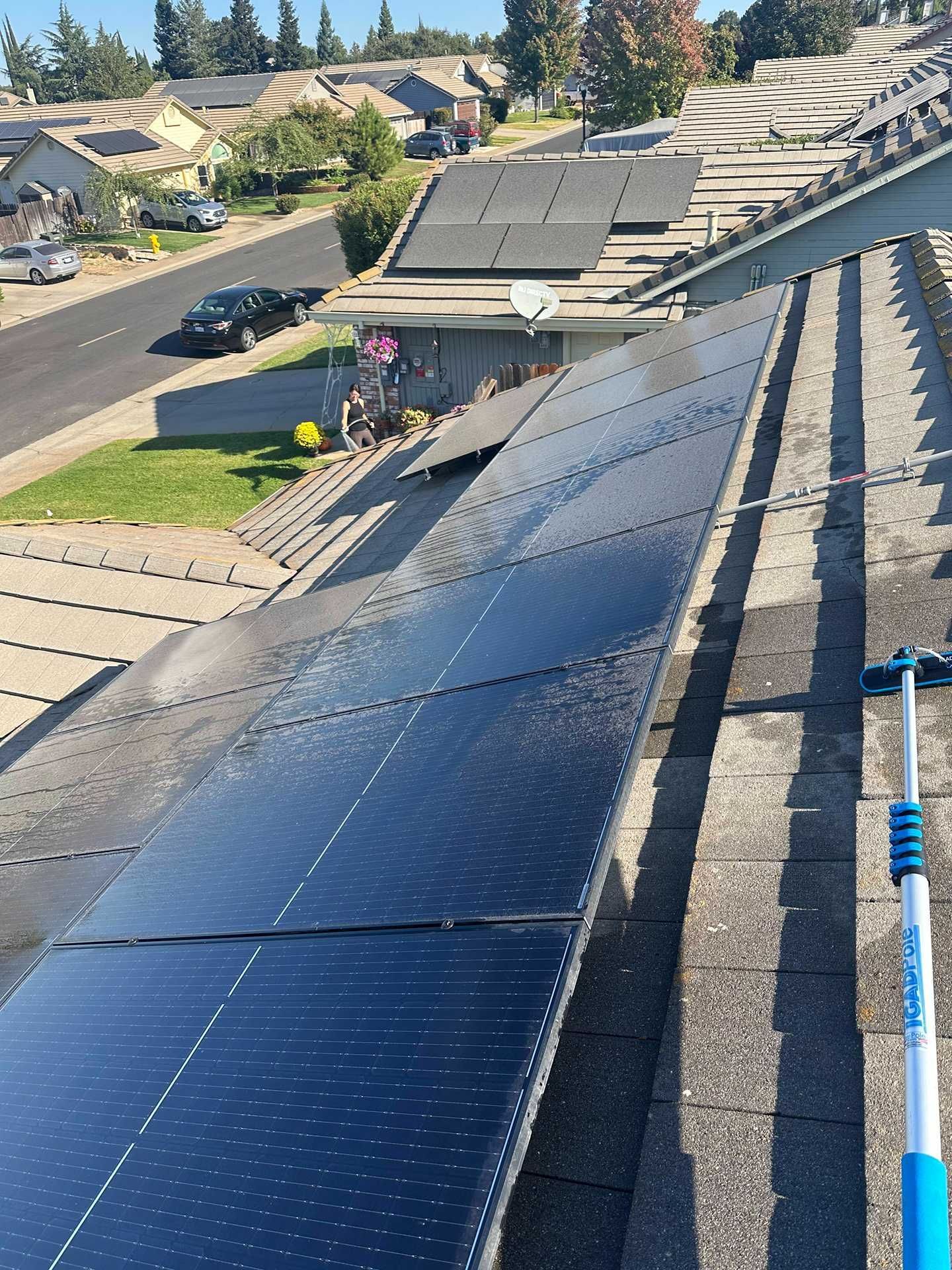 Solar panels on a sloped rooftop in a suburban neighborhood under a clear sky.