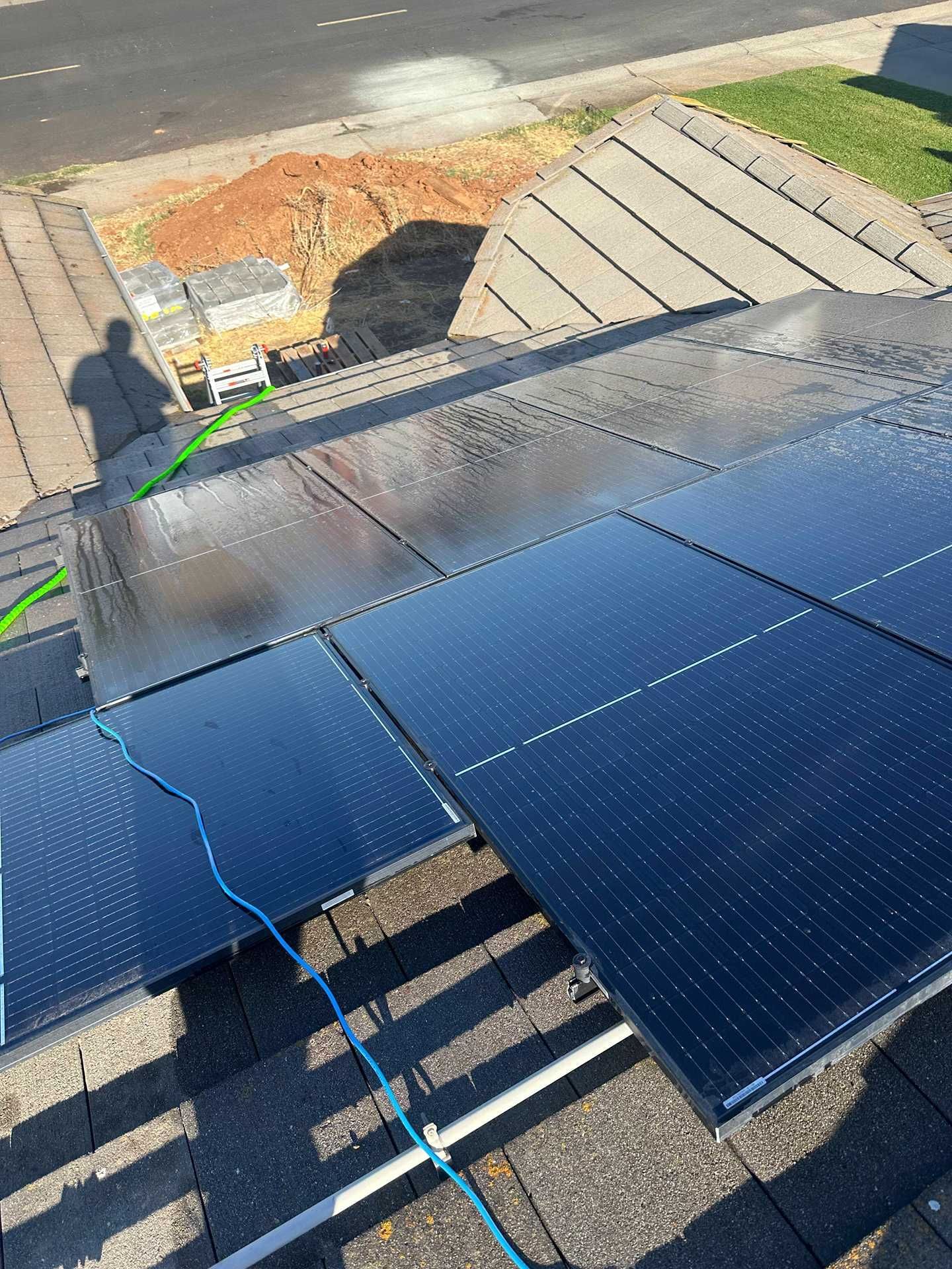 Solar panels installed on a sloped rooftop, with blue cables visible near the edge.