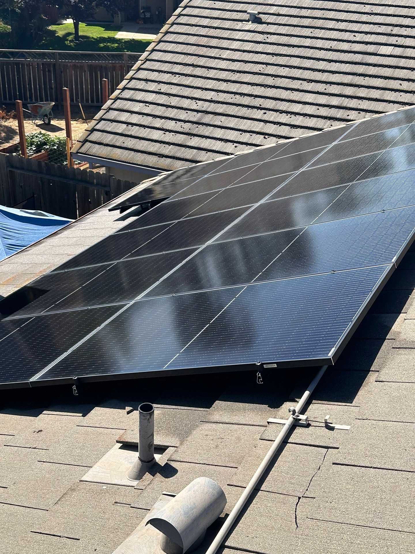 Solar panels installed on a slanted rooftop beside a house