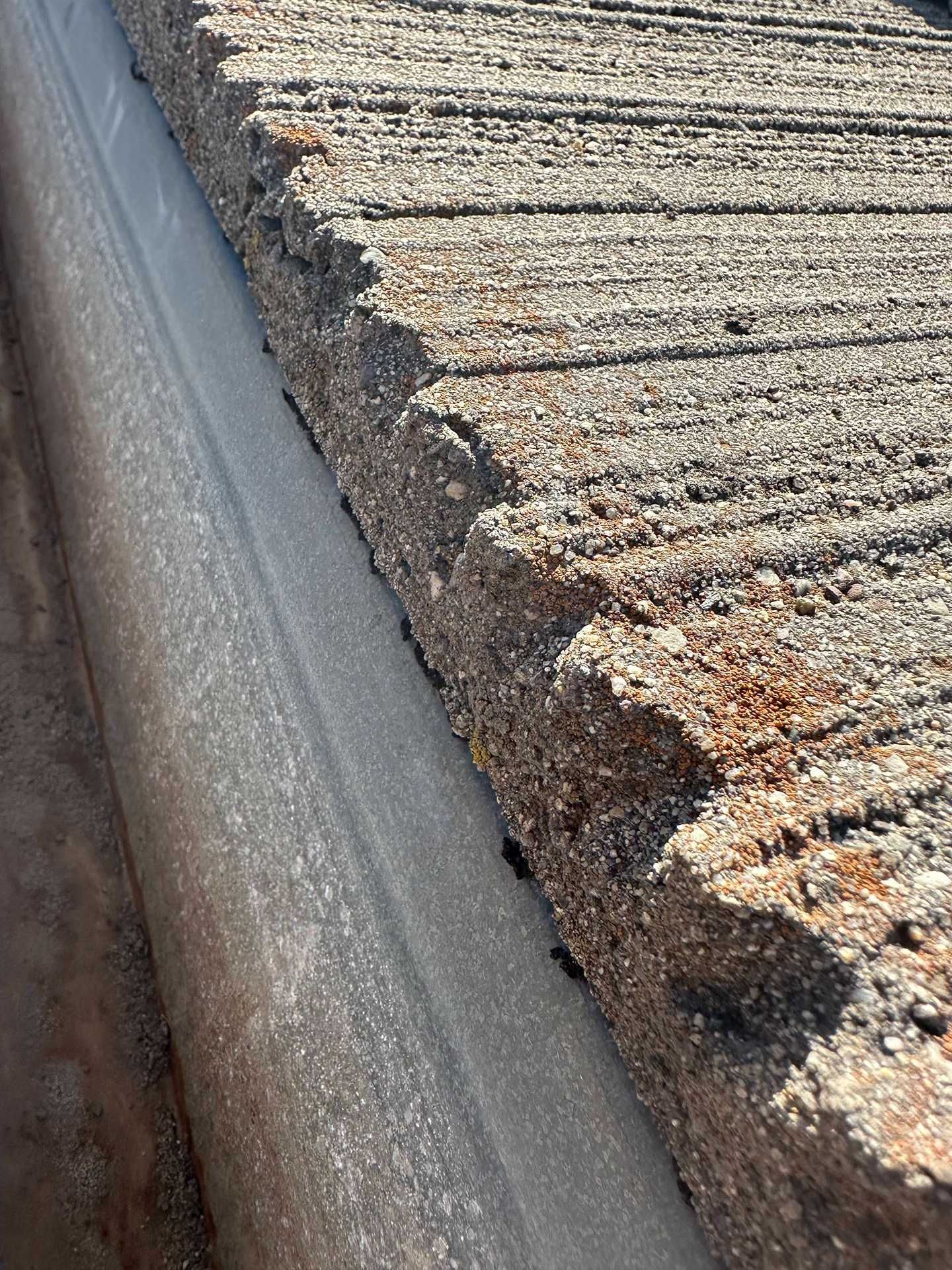 Close-up of a weathered roof edge with peeling, cracked surface and exposed dark underlayer