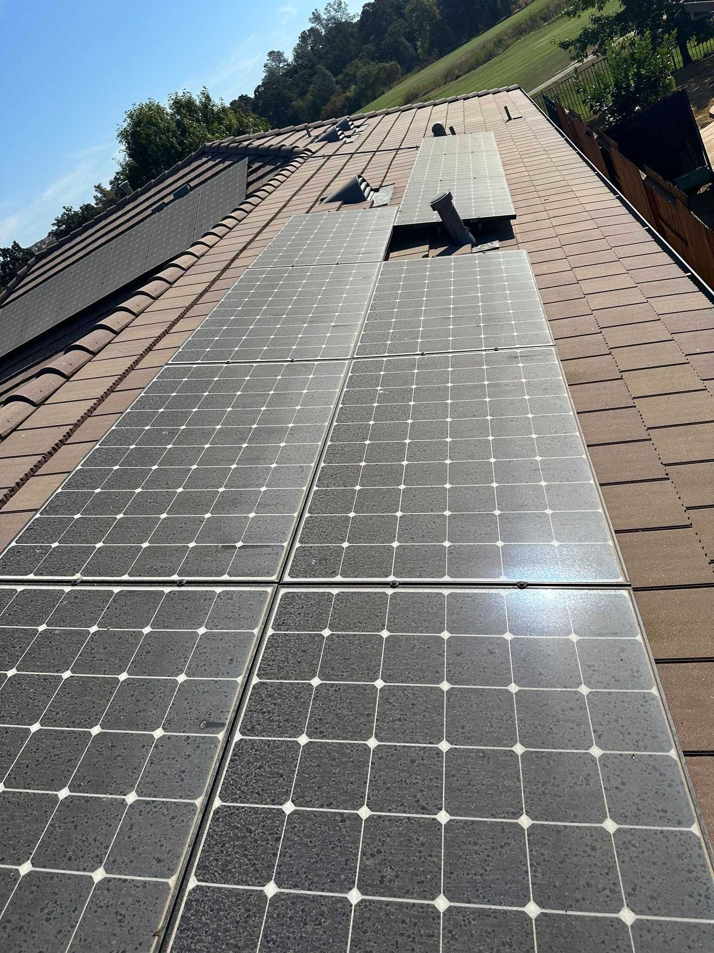 Solar panels installed on a steep tiled roof in a rural hillside setting.