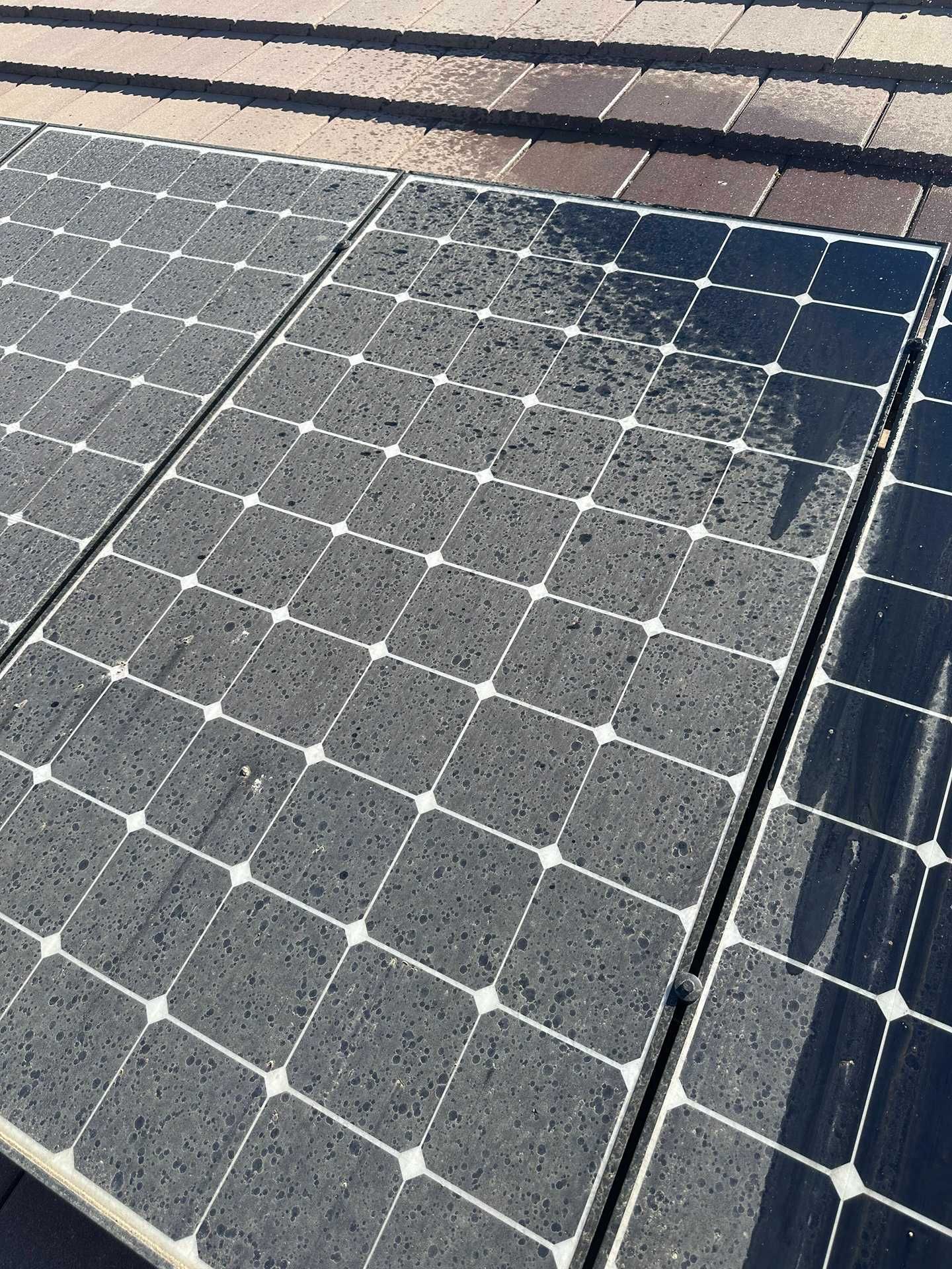 Close-up of two dusty solar panels with visible wear and a shadow across the top right corner