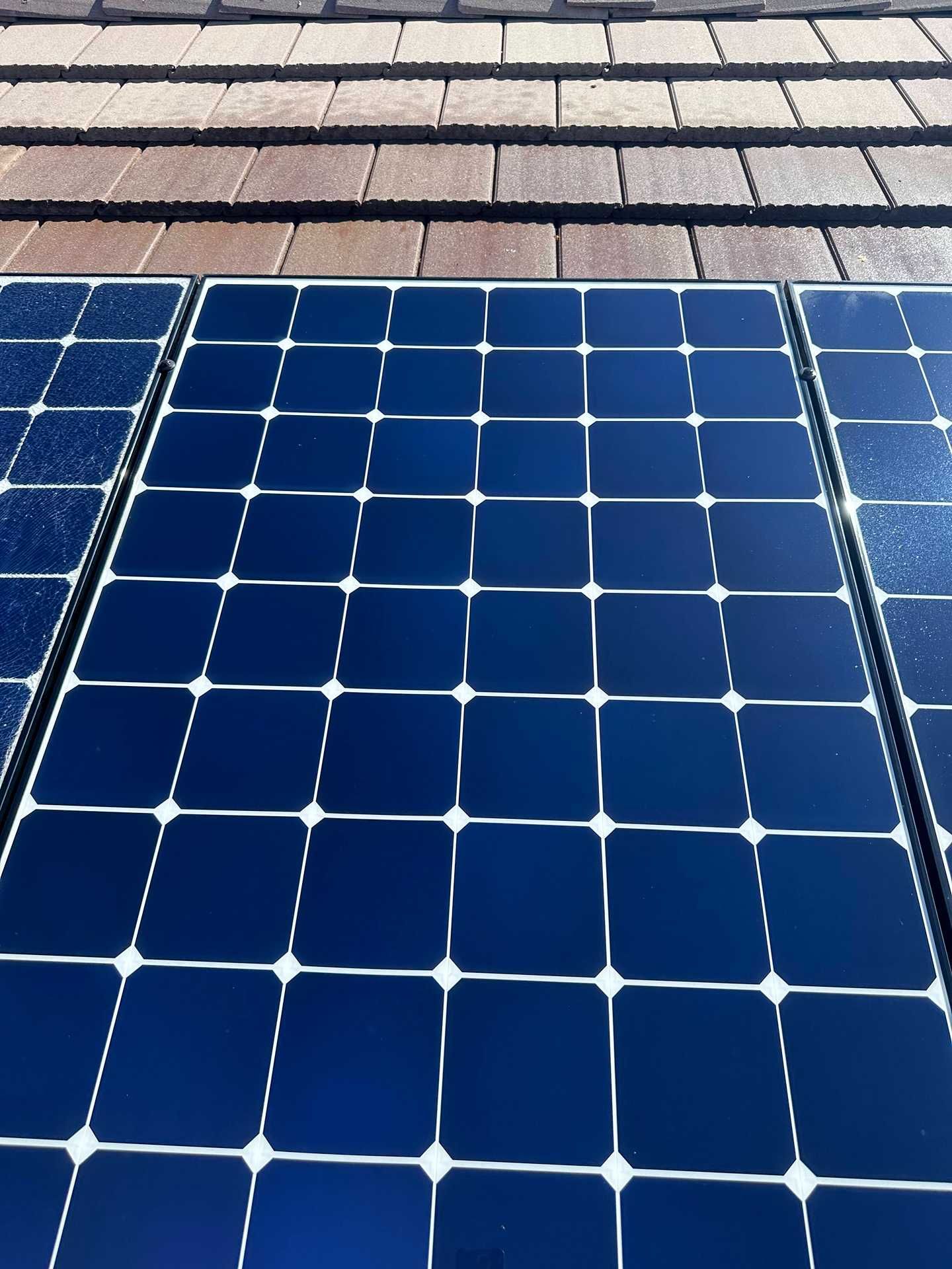 Blue solar panel on a shingled roof with sunlight reflecting on the cells