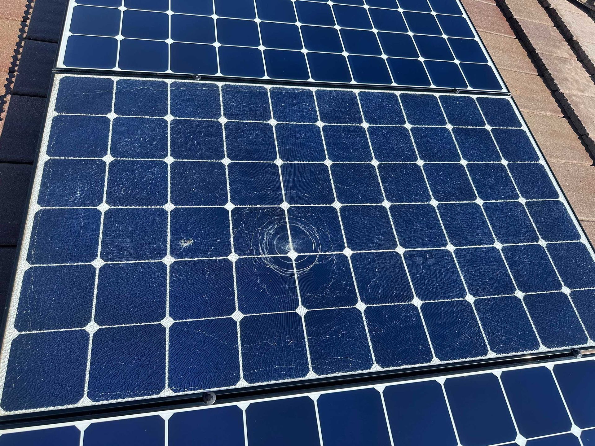Blue solar panels mounted on a roof, viewed in sunlight.