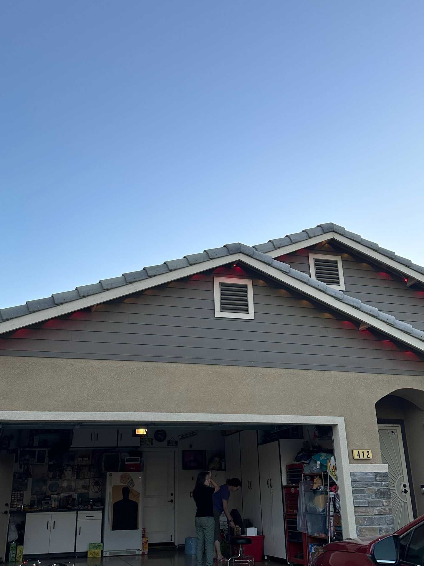 Suburban house with open garage and a person standing by the entrance under a clear sky