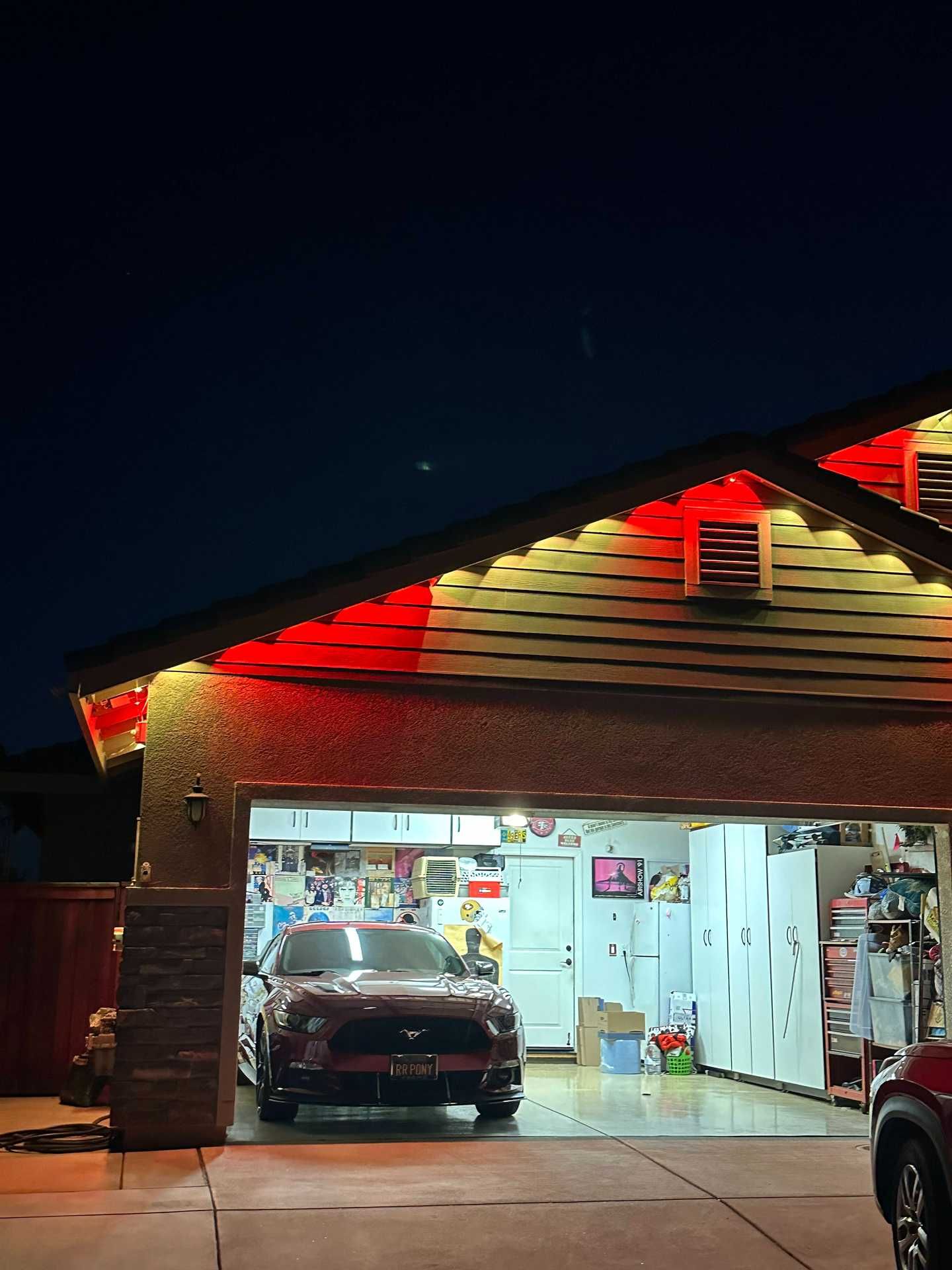 Car in a lit garage at night, with red roof lights and another vehicle partly visible on the right