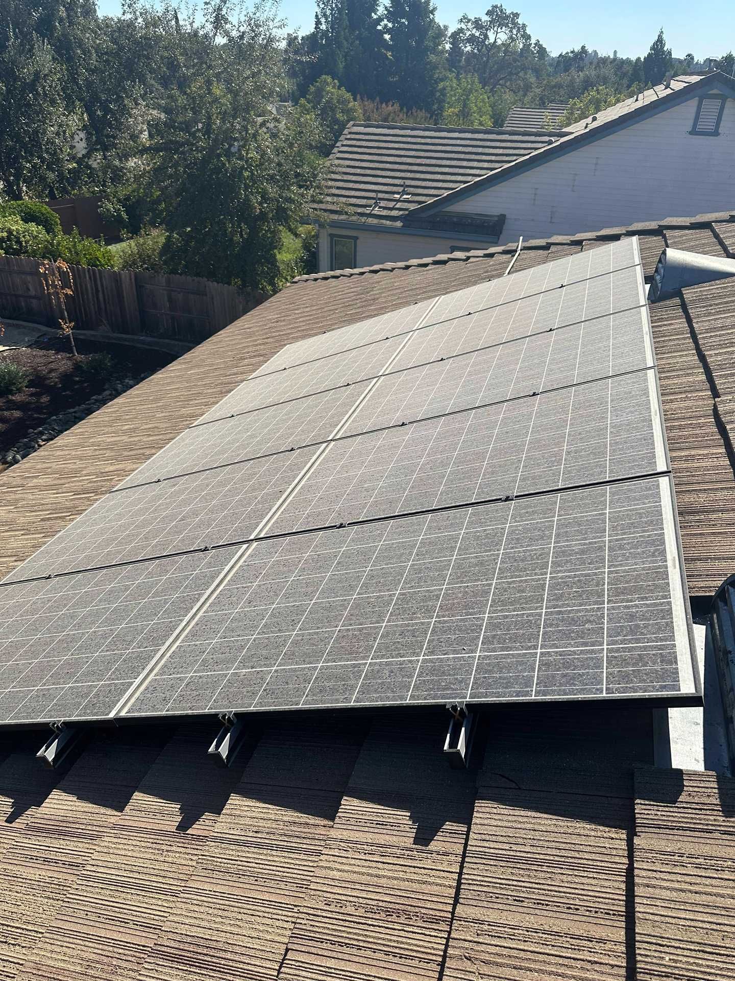 Solar panels mounted on a sloped rooftop in bright sunlight