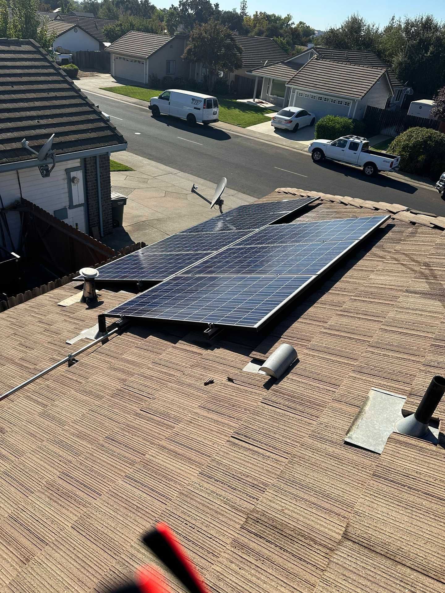 Rooftop solar panels installed on a tan shingle roof in a suburban neighborhood