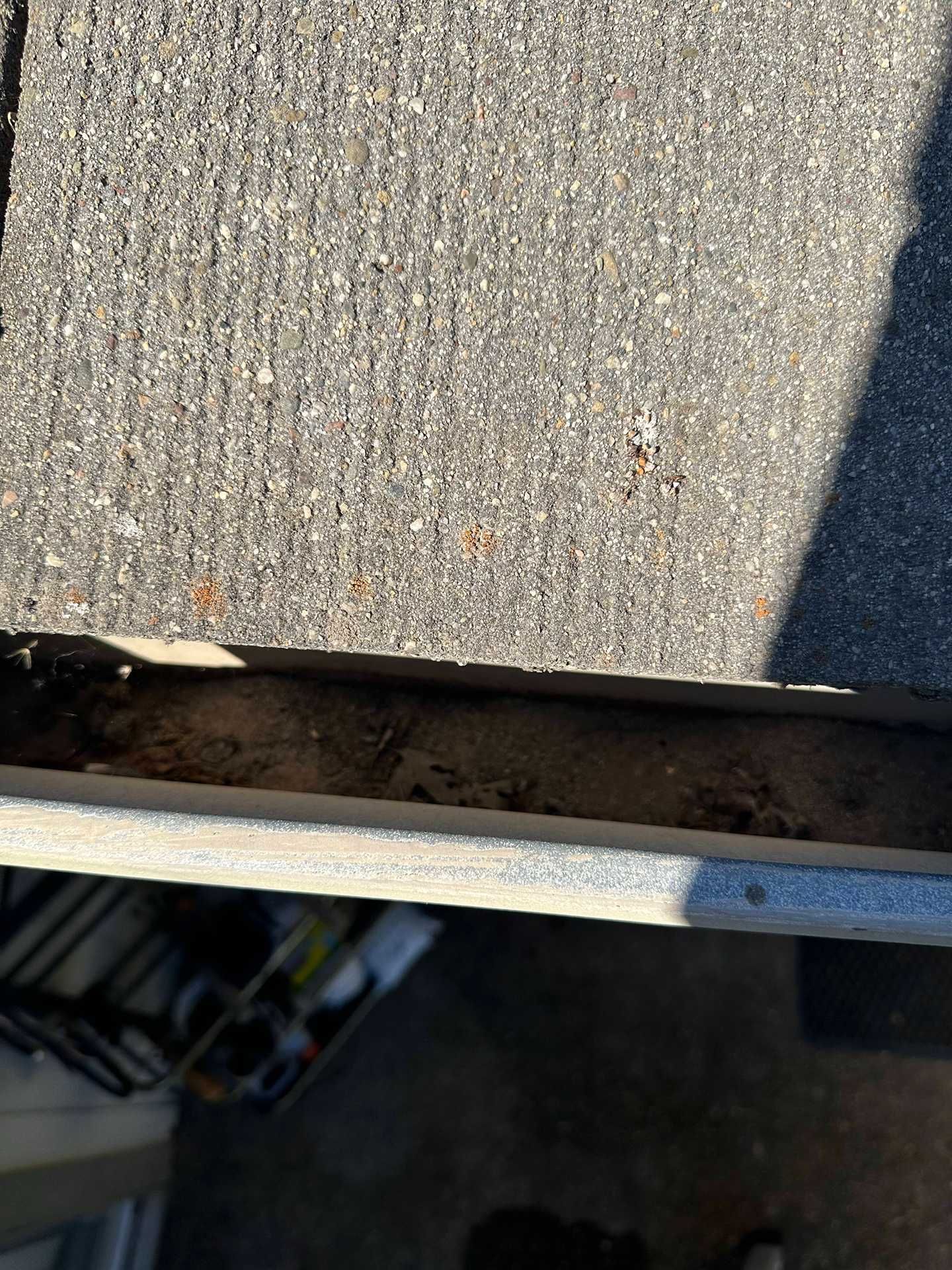 Close-up of a weathered gray surface with a dark gap along the edge and a shadow on the right.