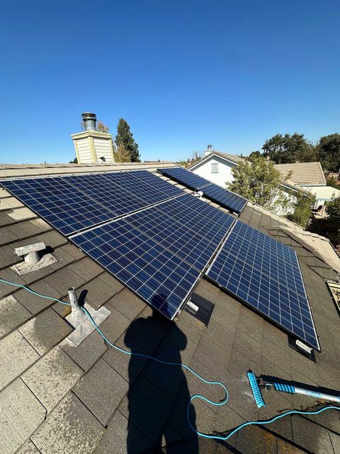Solar panels installed on a shingled roof under a clear blue sky