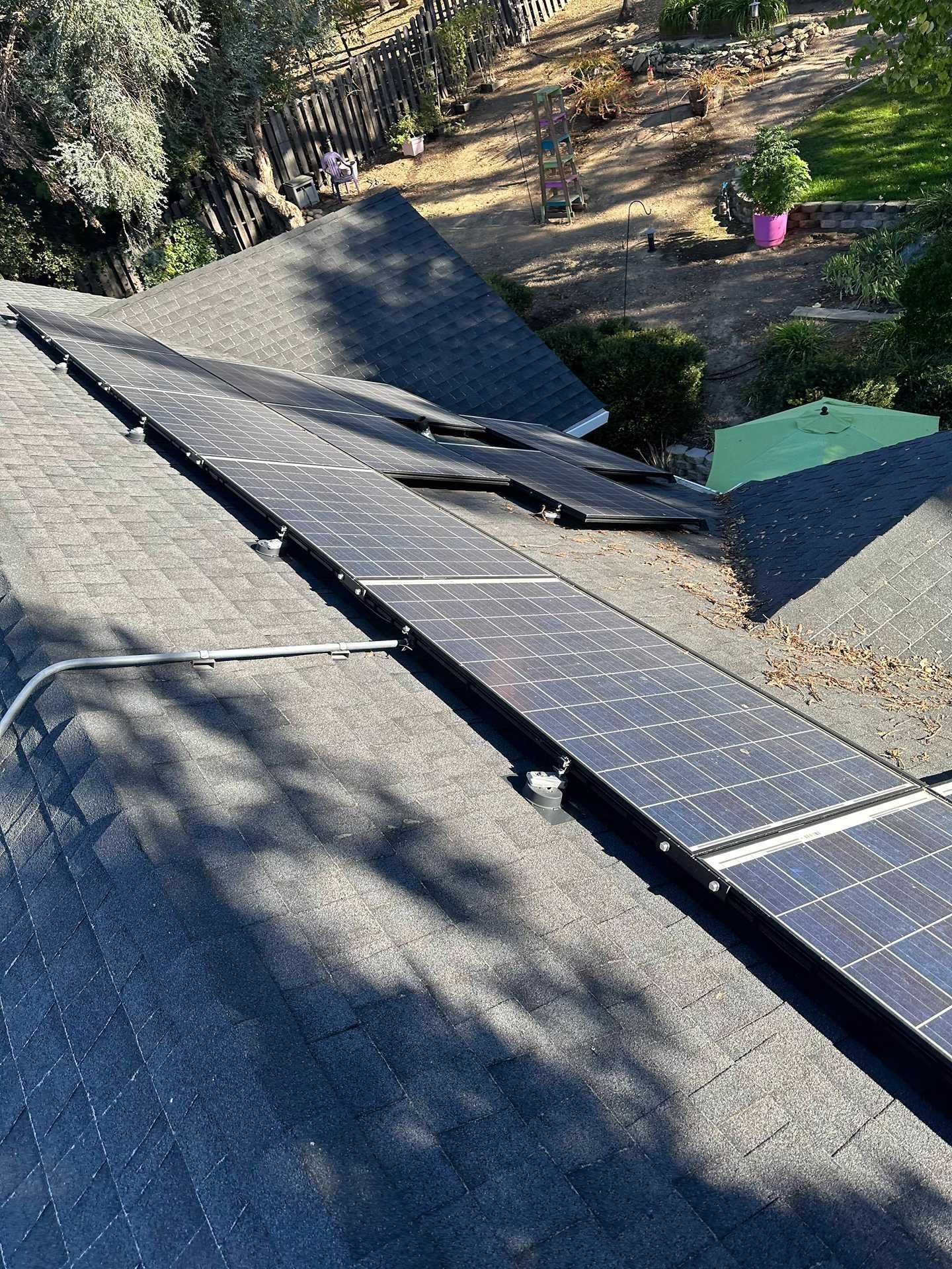 Solar panels on a sloped roof with damaged or lifted sections, viewed from above.