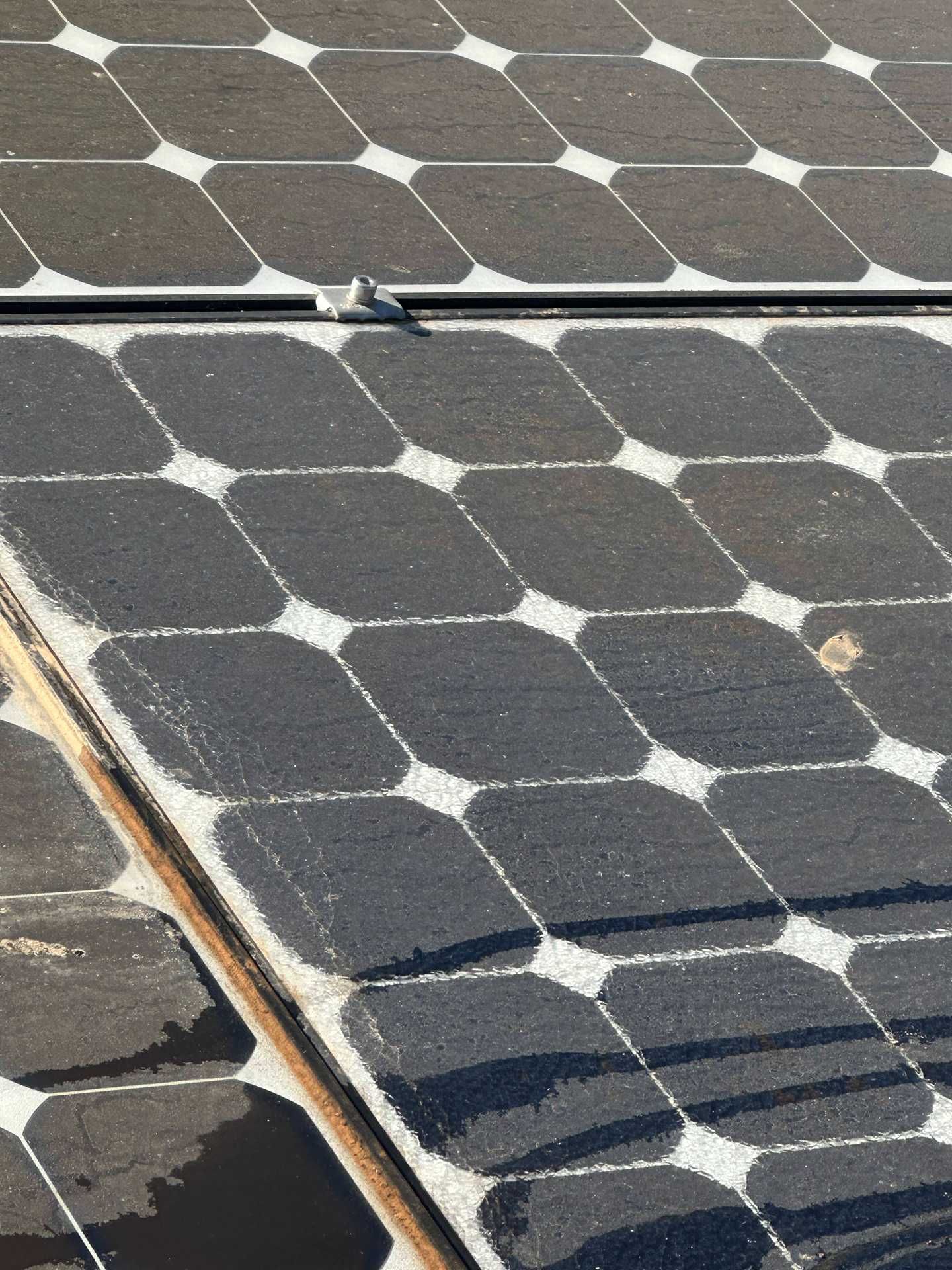 Solar panels covered in melting snow, with dark panels exposed in patches.