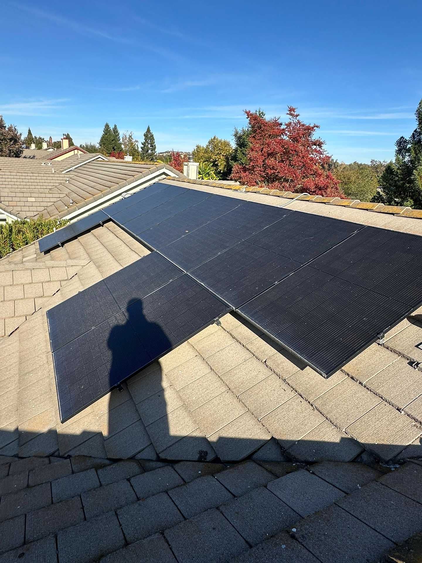 Solar roof panels installed on a shingled rooftop under a clear blue sky.