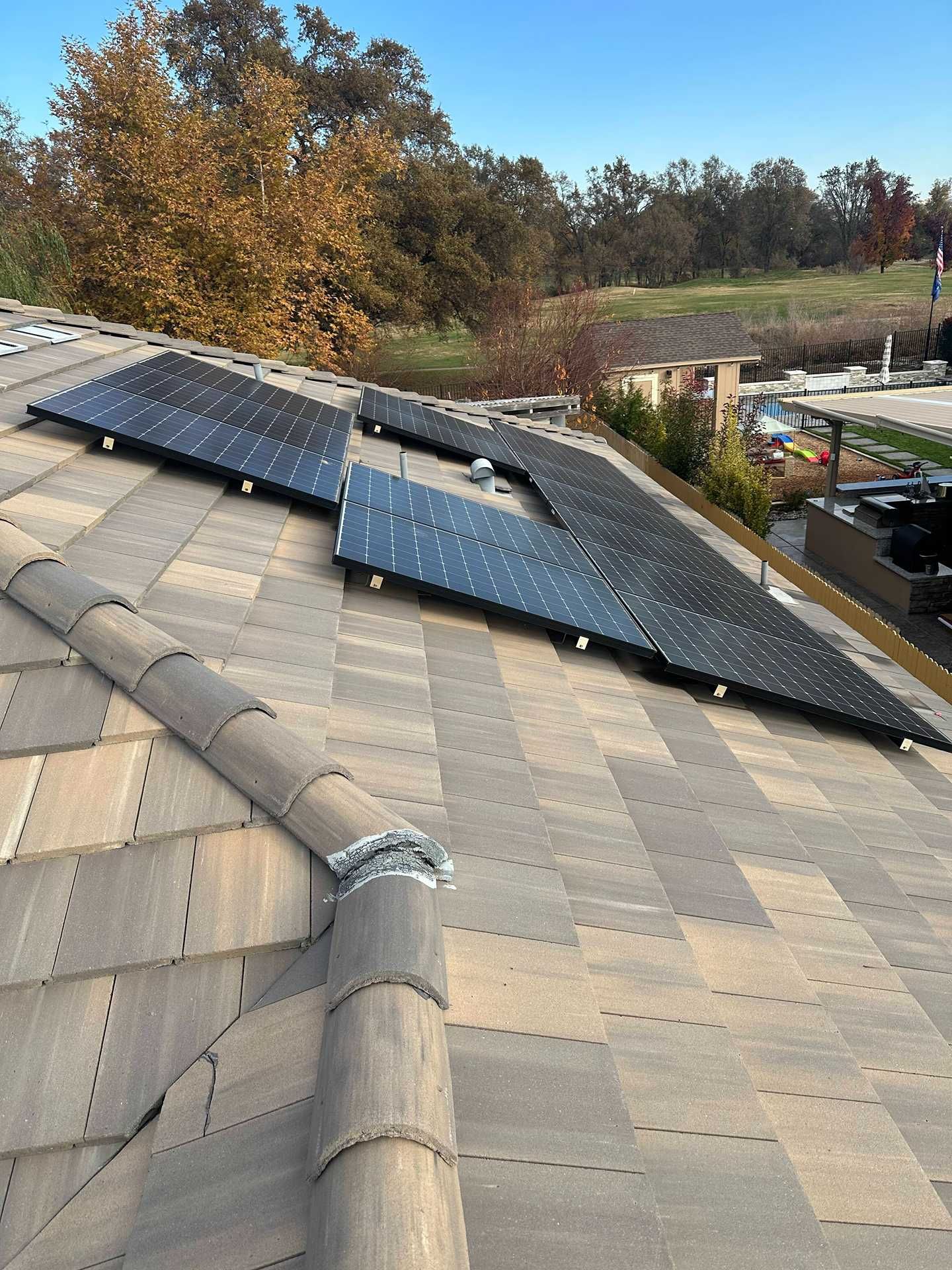 Roof with solar panels and a damaged section, viewed from above in a suburban area.