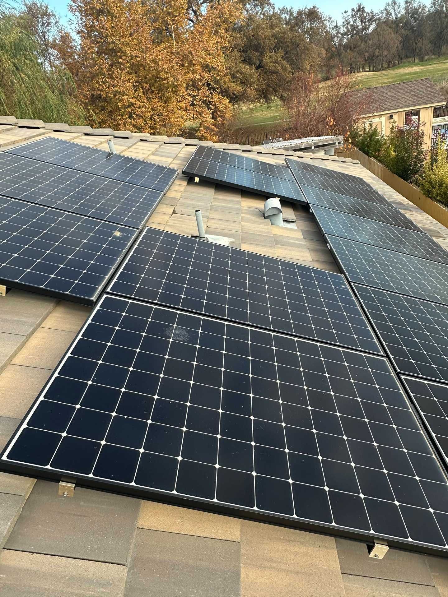 Rooftop solar panels installed around a central skylight, with autumn trees in the background.