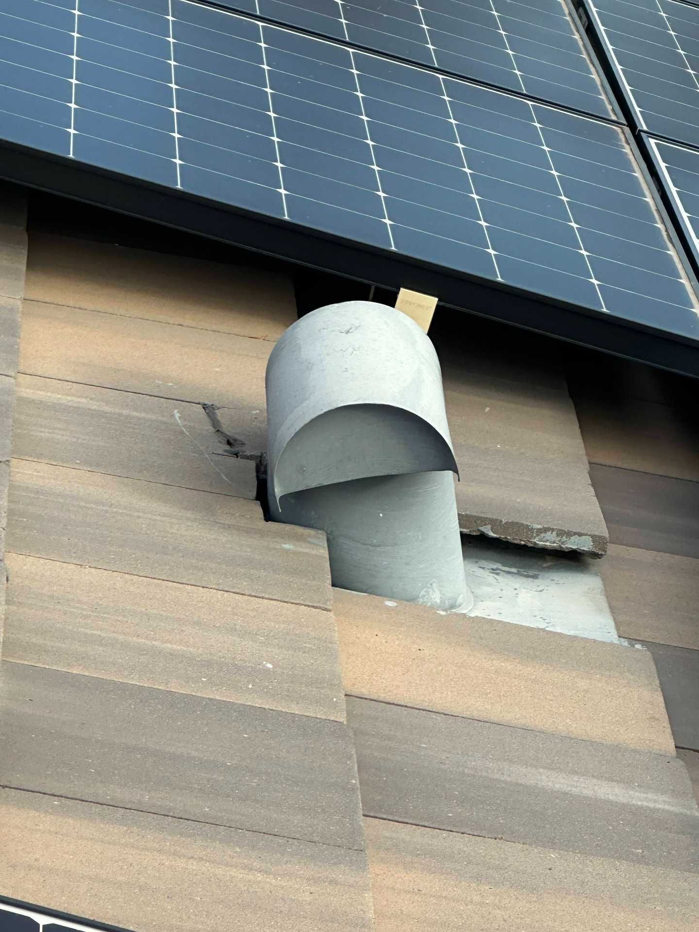 Rooftop solar panels above a gray roof vent chimney