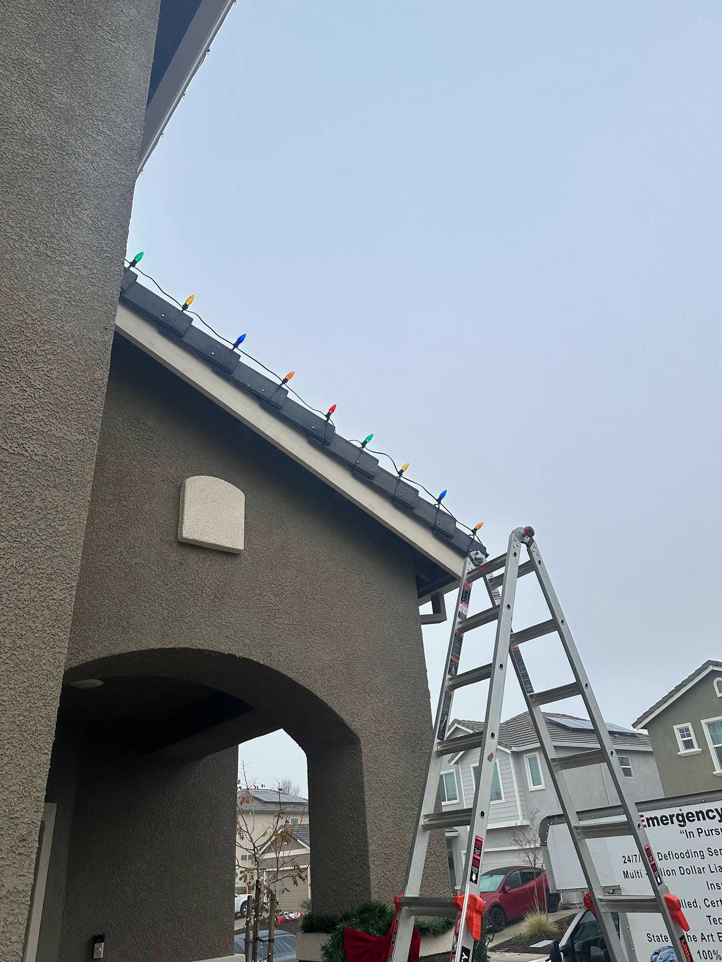 Ladder leaning against a gray house under construction, with a cloudy sky overhead.
