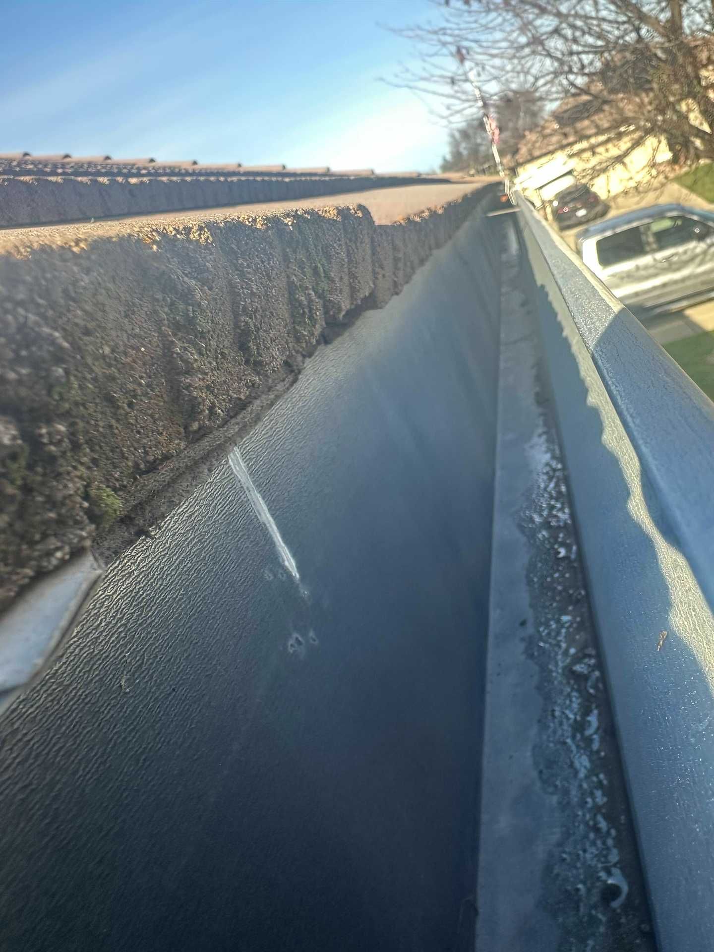 Frozen roadside ditch beside a snowy embankment and parked car in winter sunlight