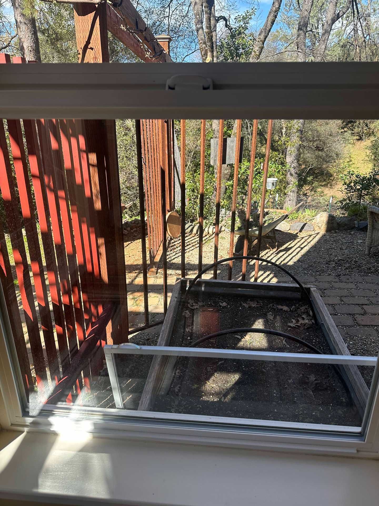 Outdoor stair lift by a red fence, viewed through a window on a sunny day
