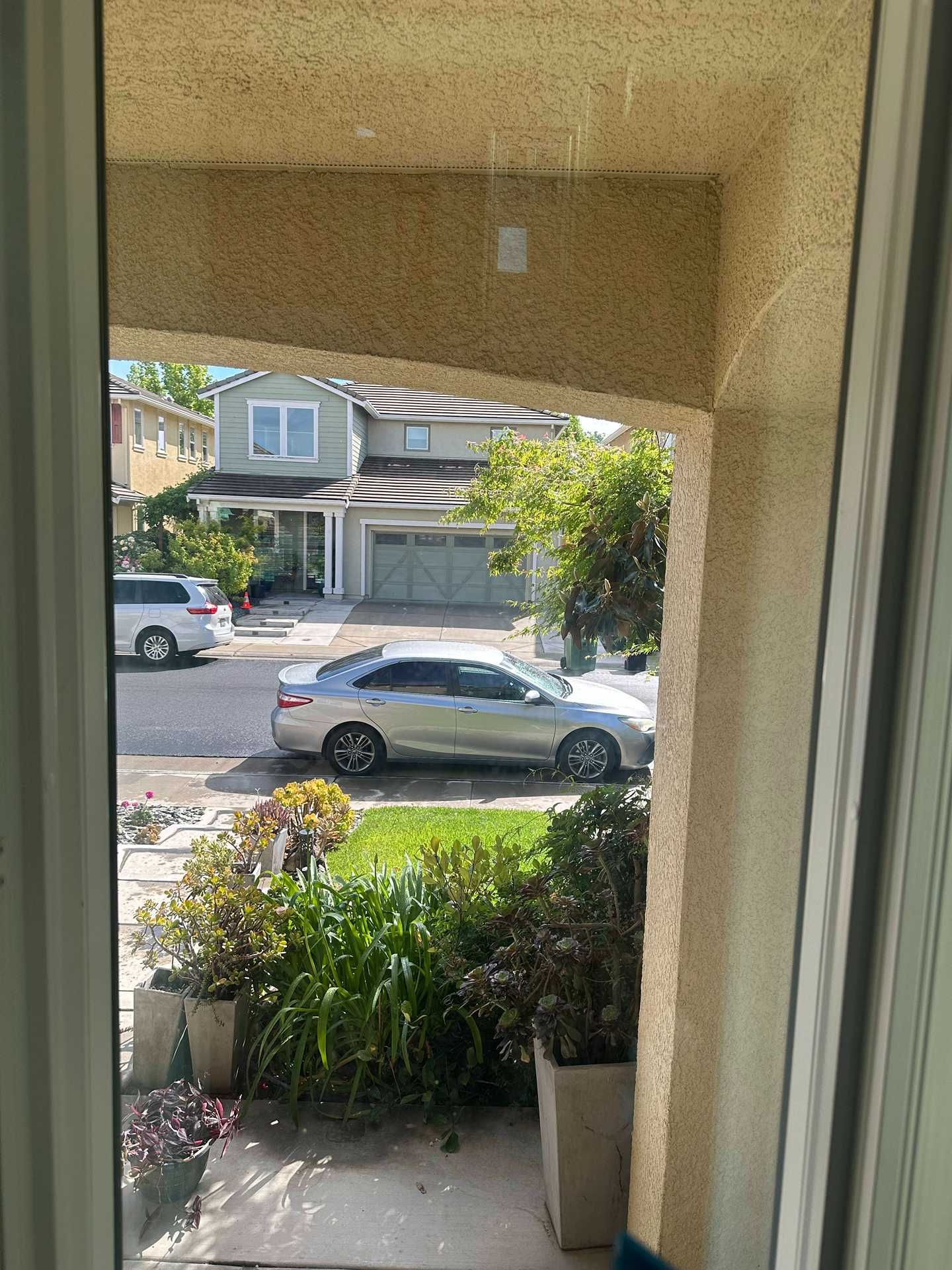 Front porch view of a quiet suburban street with parked cars and houses across the road
