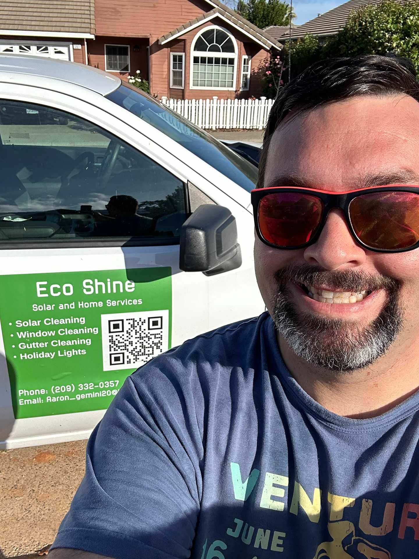 Smiling man takes selfie beside a green Eco Shine car door sign in a driveway.
