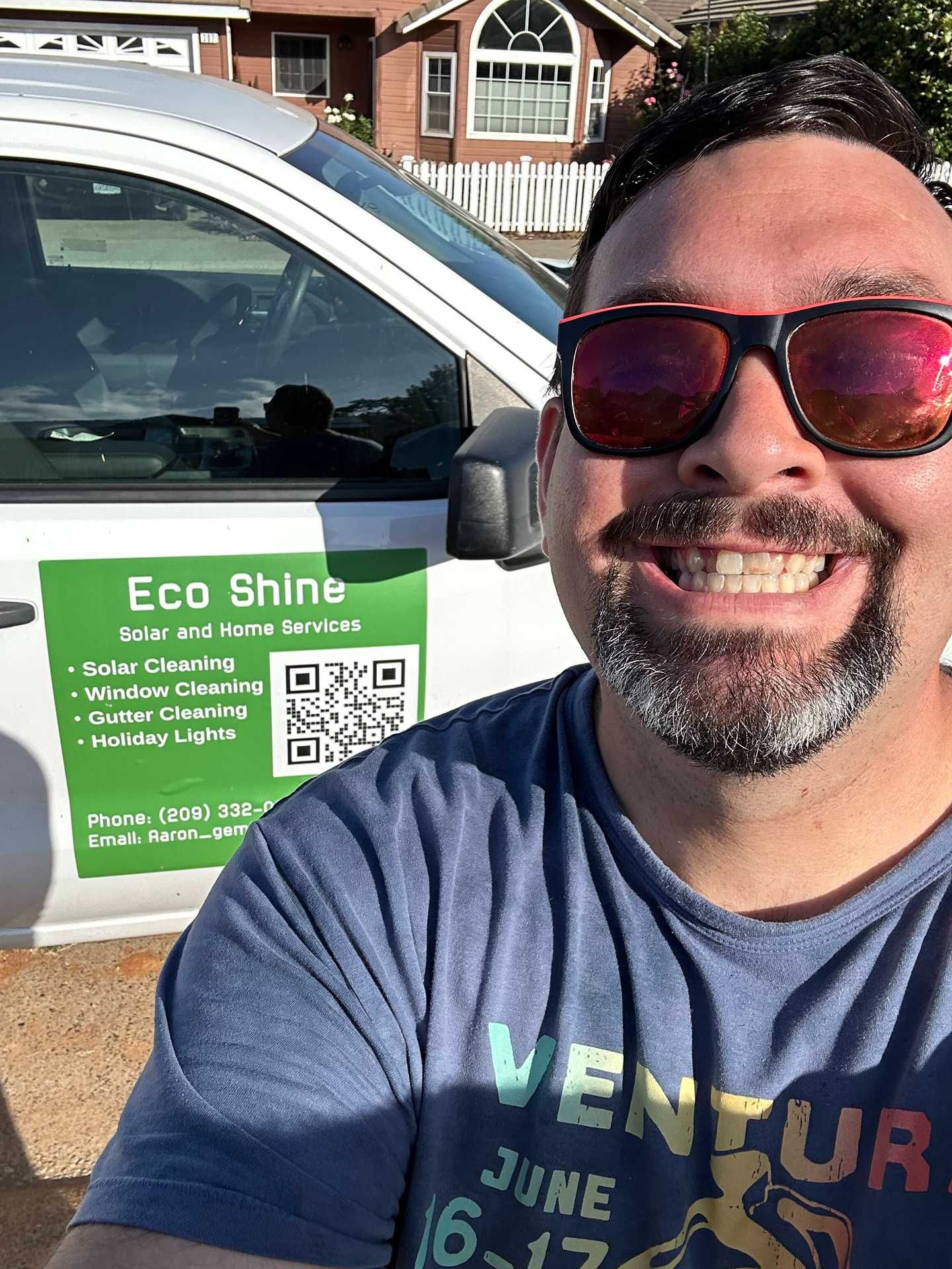 Smiling man taking a selfie beside a white car with an Eco Shine sign on the door.