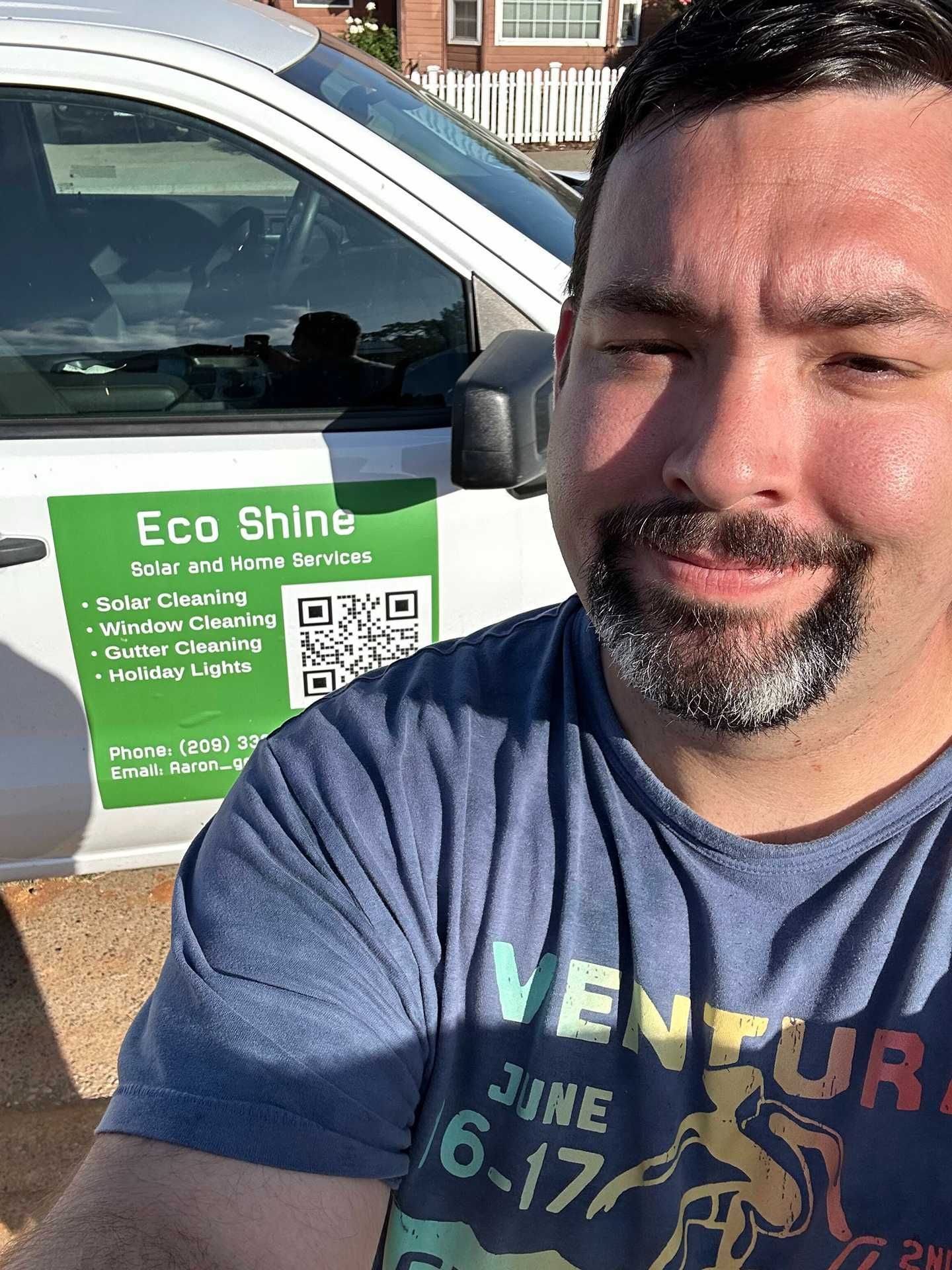 Man in blue shirt posing beside car with green “Eco Shine” sign on the door