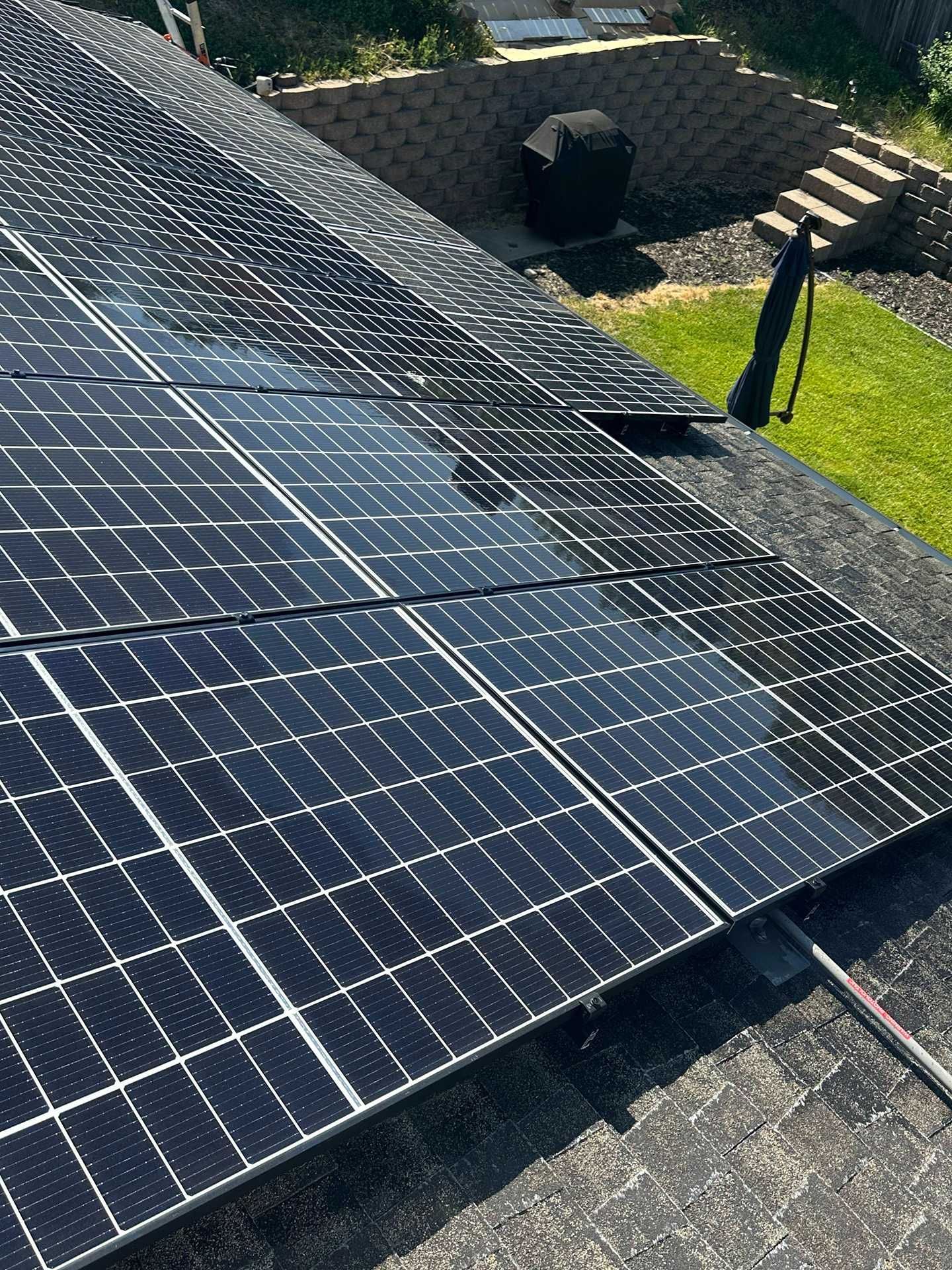 Solar panels covering a rooftop beside a grassy yard and stone steps