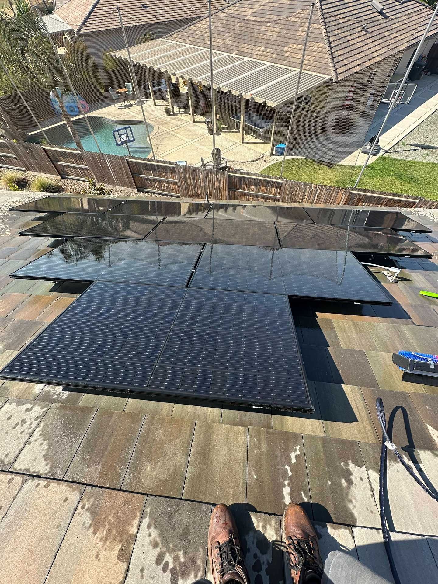 View from a rooftop pool deck with water, tan stone tiles, and lounge chairs below.