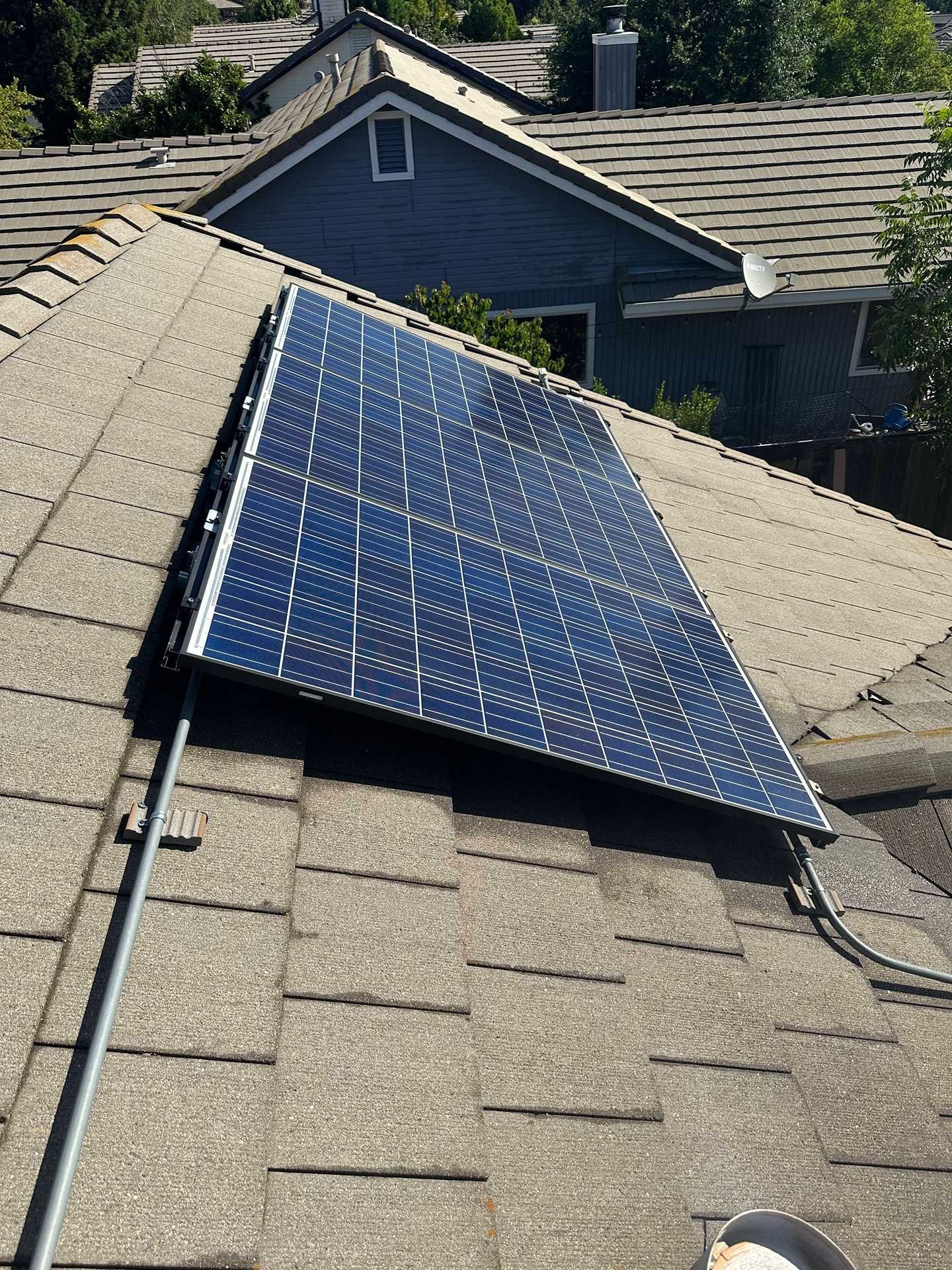 Solar panels mounted on a sloped shingle roof in a residential neighborhood