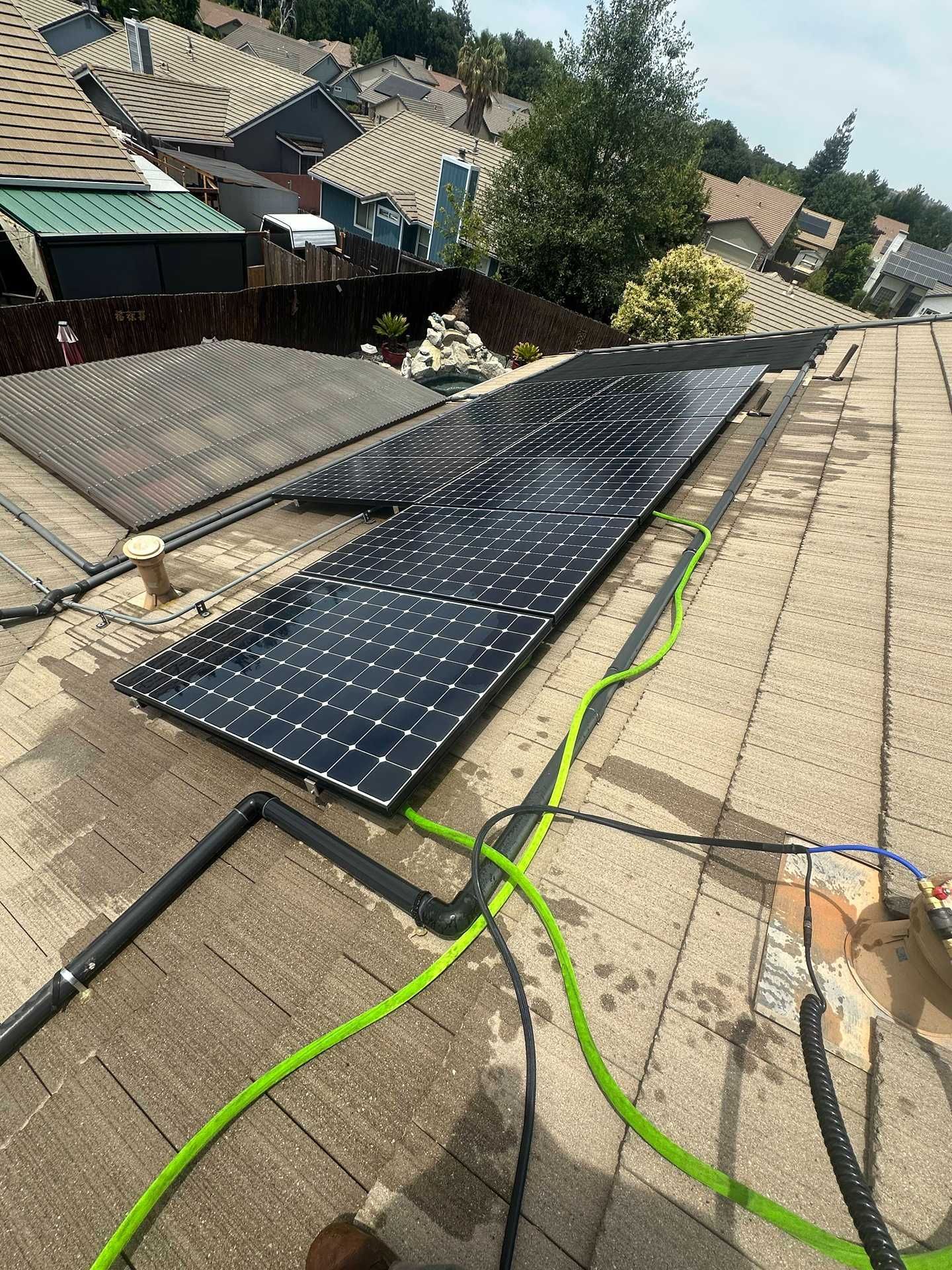 Solar panels laid out on a sloped rooftop during installation, with cables visible.