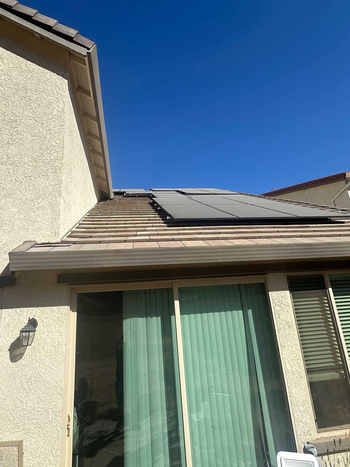 House exterior with solar panels on the roof under a clear blue sky