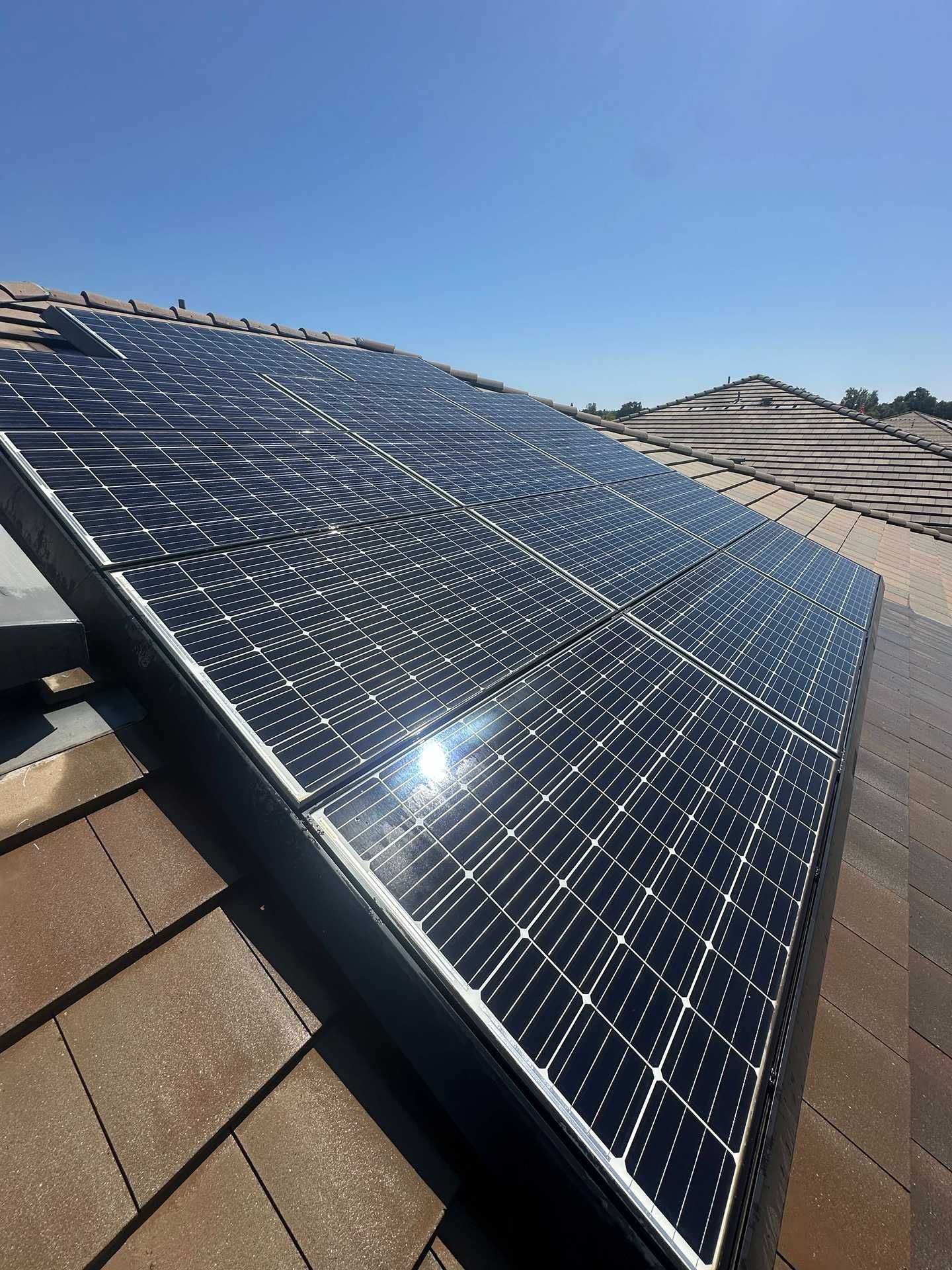 Solar panels installed on a shingled rooftop under a clear blue sky.