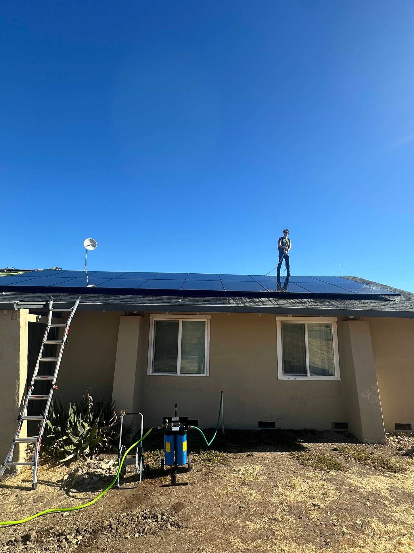 Two workers on a house roof installing black roofing under a clear blue sky