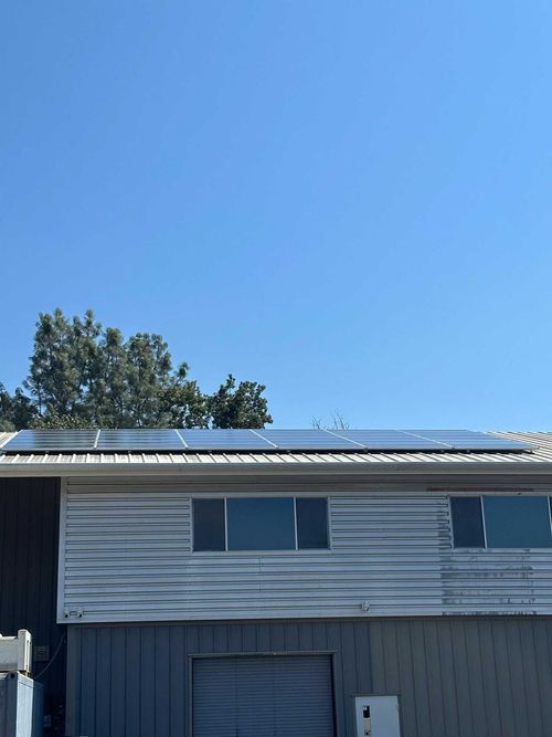 Blue two-story house with a solar-paneled roof under a clear sky