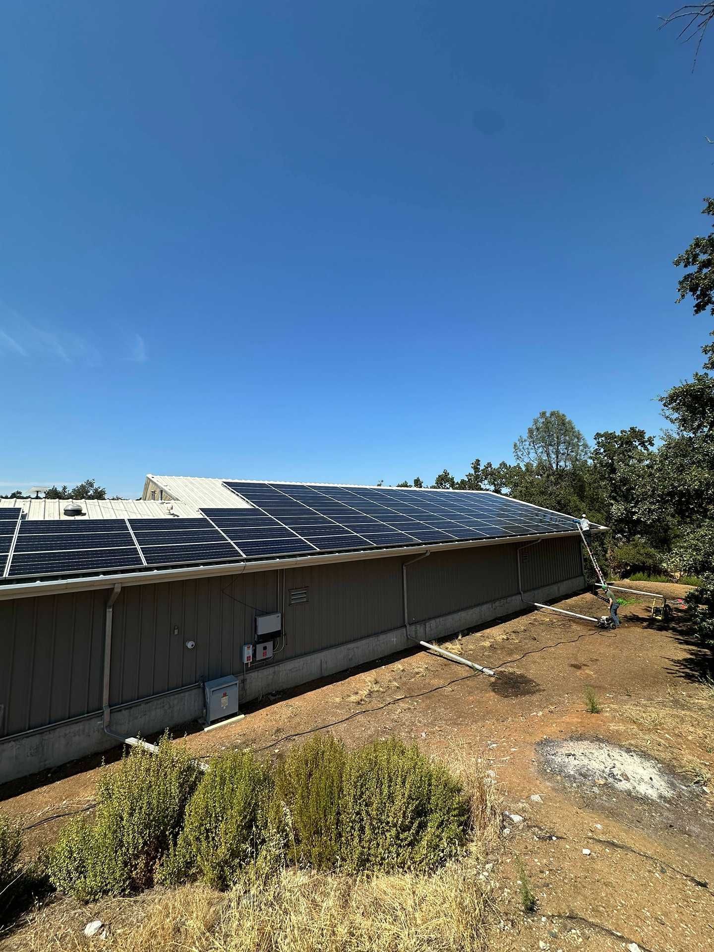 Roof with solar panels beside a dry yard under a clear blue sky