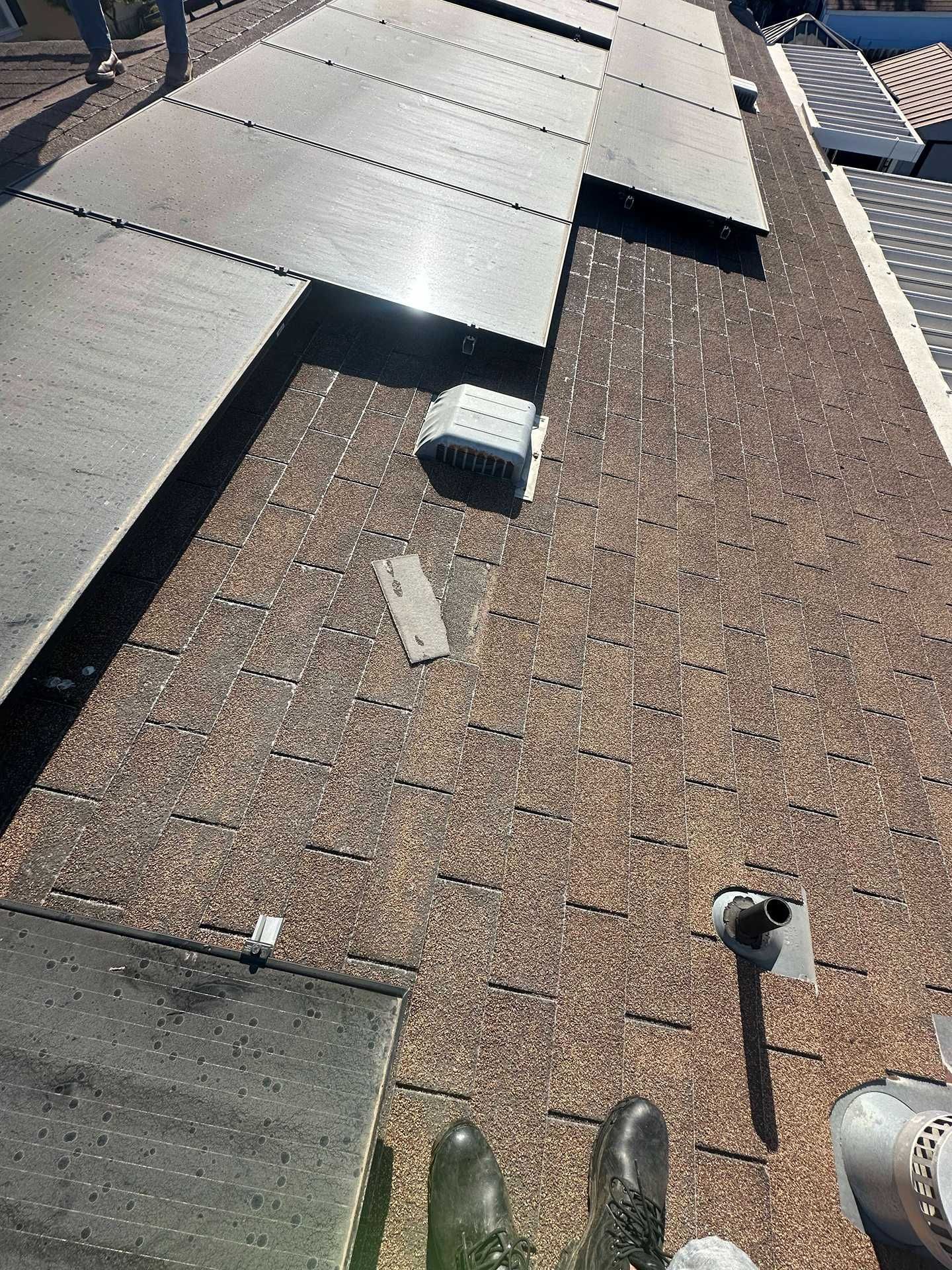 Rooftop with solar panels and vents on a gravel-covered flat roof under bright sunlight