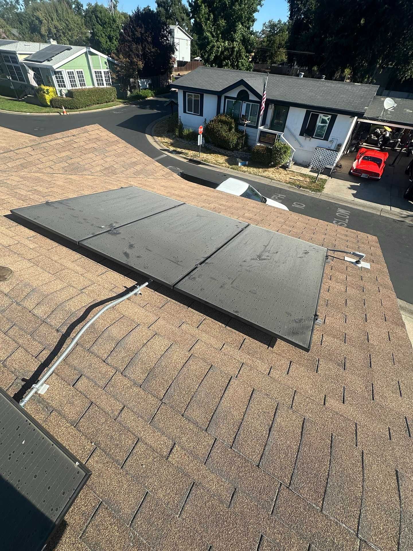 Roof with solar panels on a house in a suburban neighborhood, viewed from above.