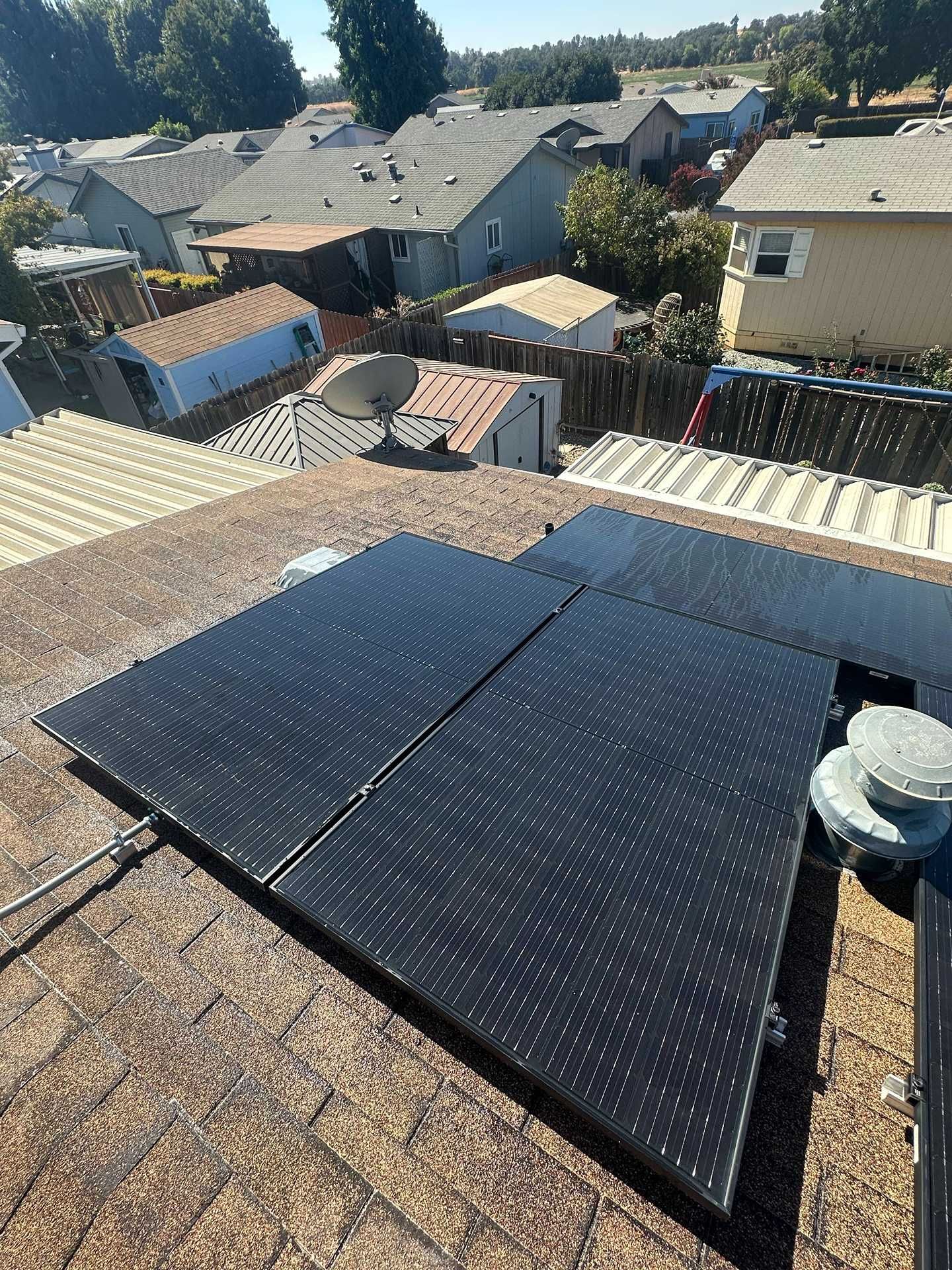 Solar panels on a rooftop in a suburban neighborhood under bright sunlight.