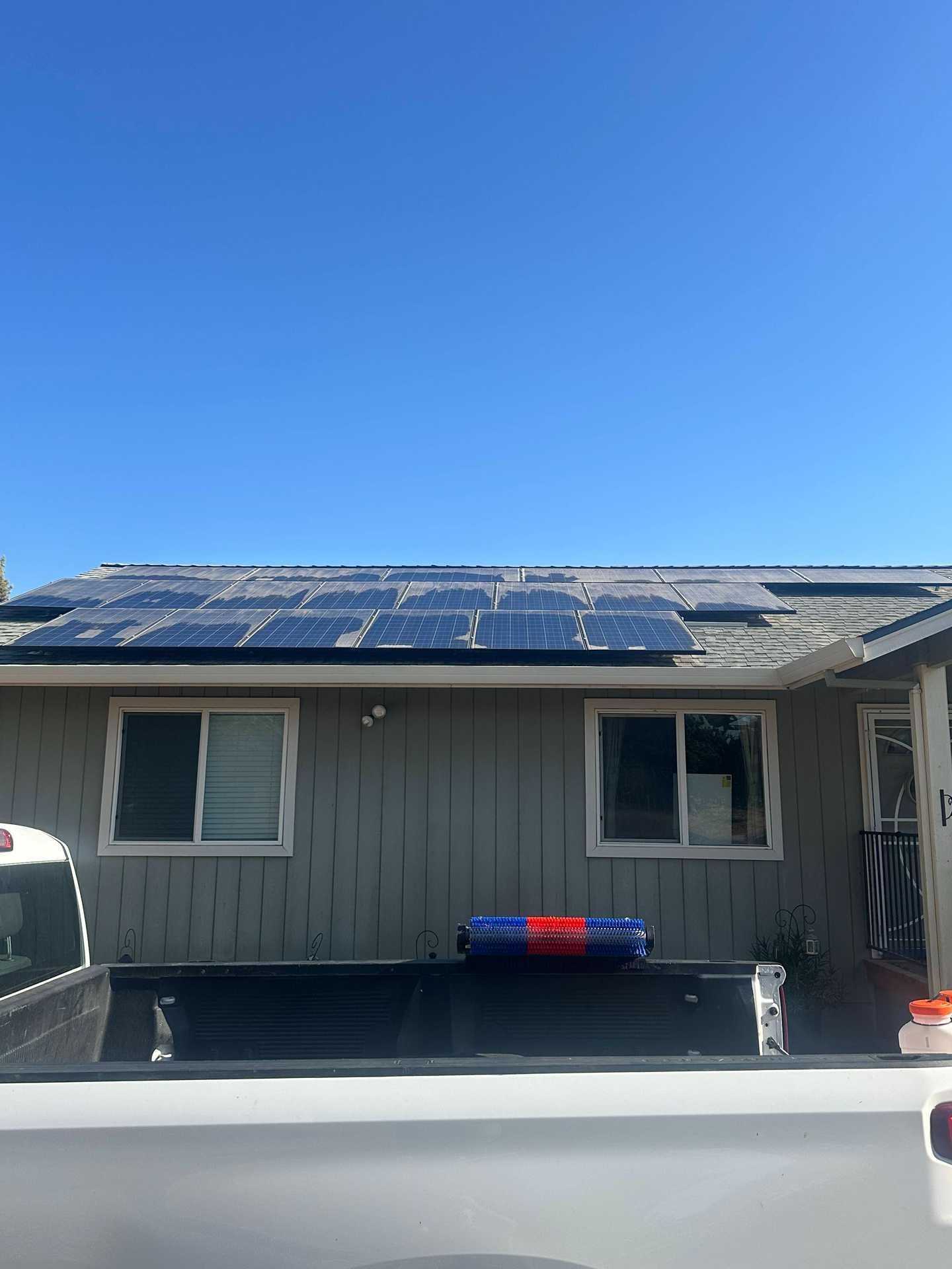 Single-story house with solar panels on the roof and a white truck parked in front.