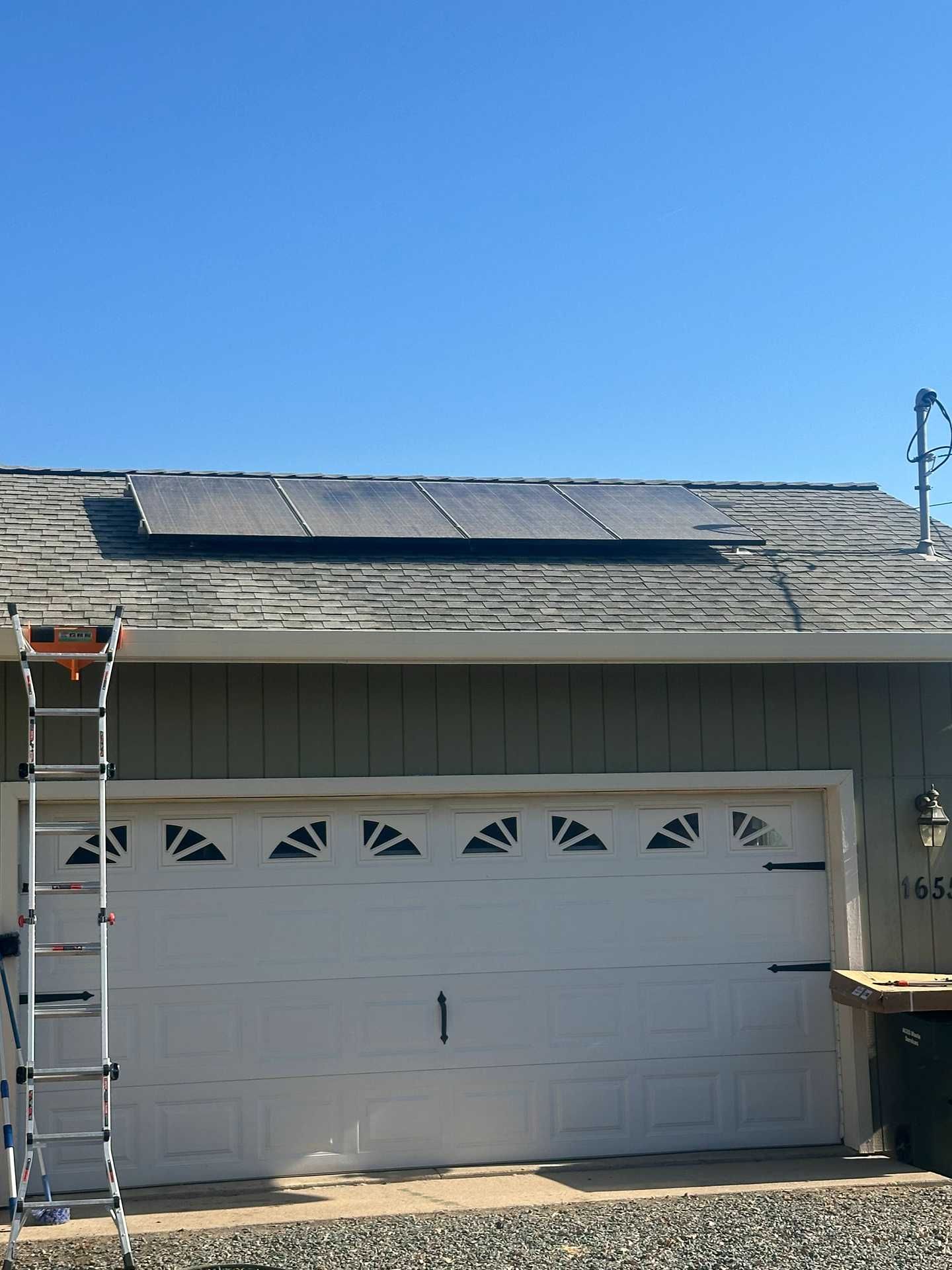 House roof with solar panels and a ladder under a clear blue sky