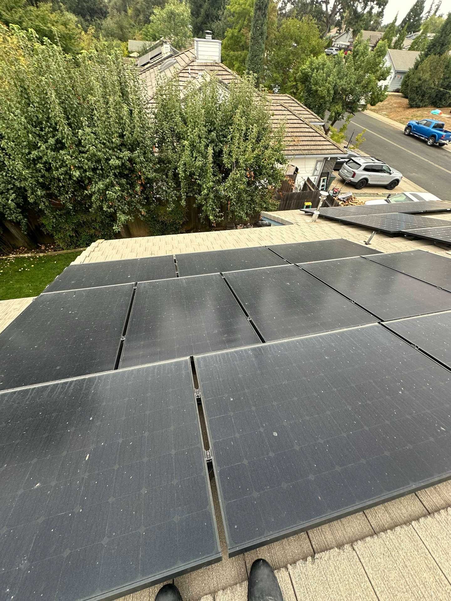 Roof with black solar panels overlooking trees and a street below