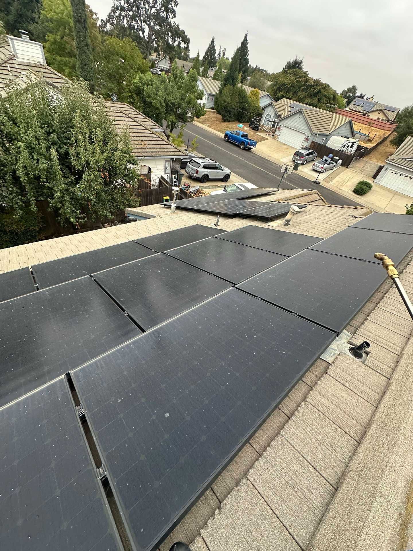 Tilted rooftop solar panels overlooking a sloped residential neighborhood after roof damage.