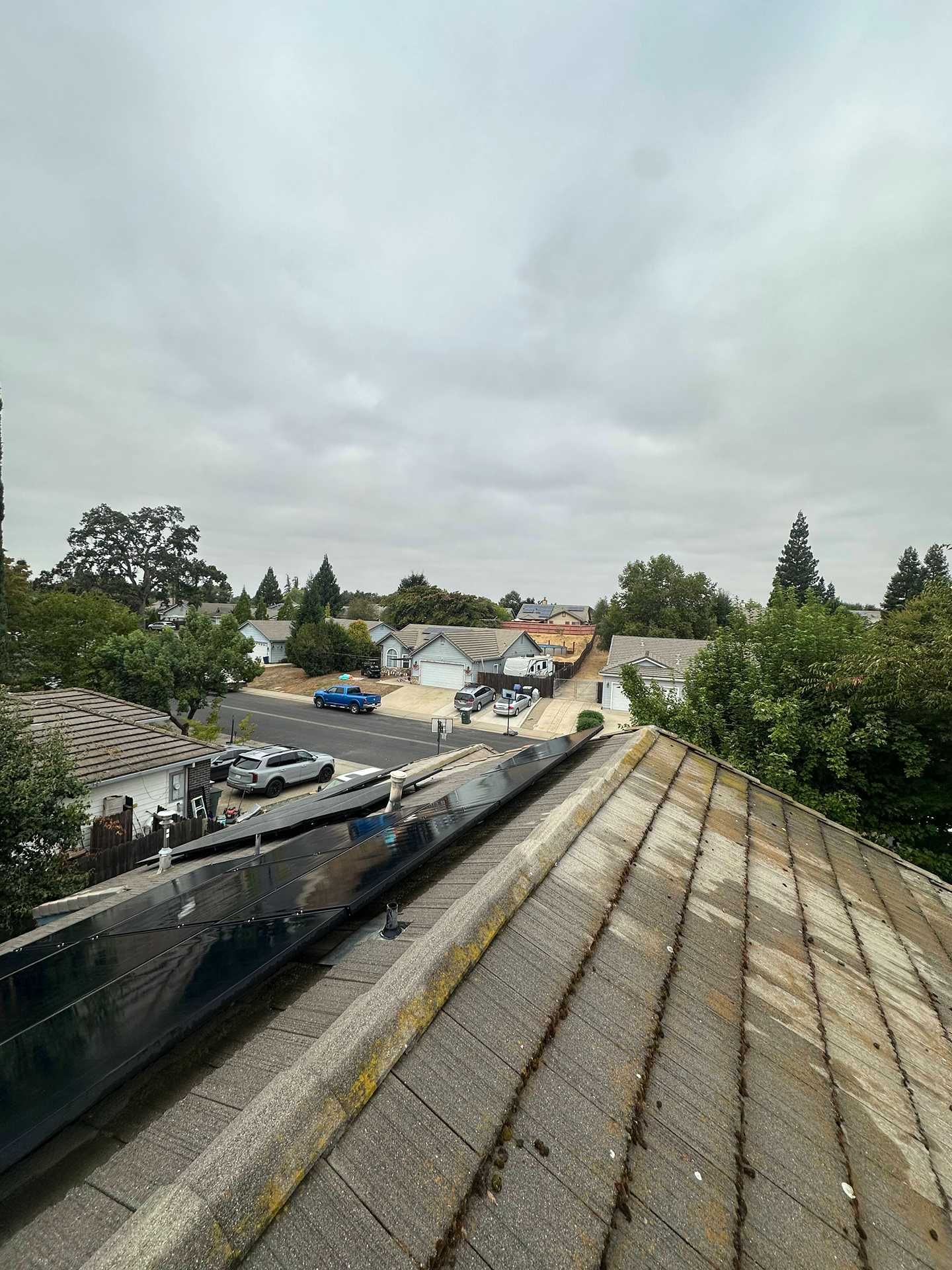 Rooftop view over a construction site and nearby houses under a cloudy sky