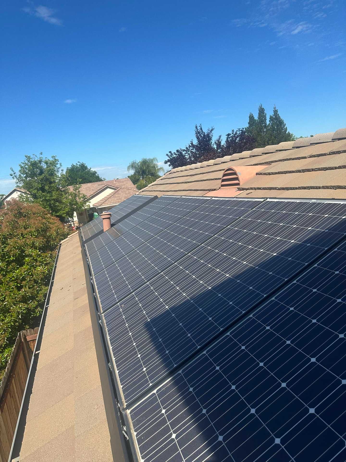 Solar panels installed on a sloped roof under a clear blue sky.