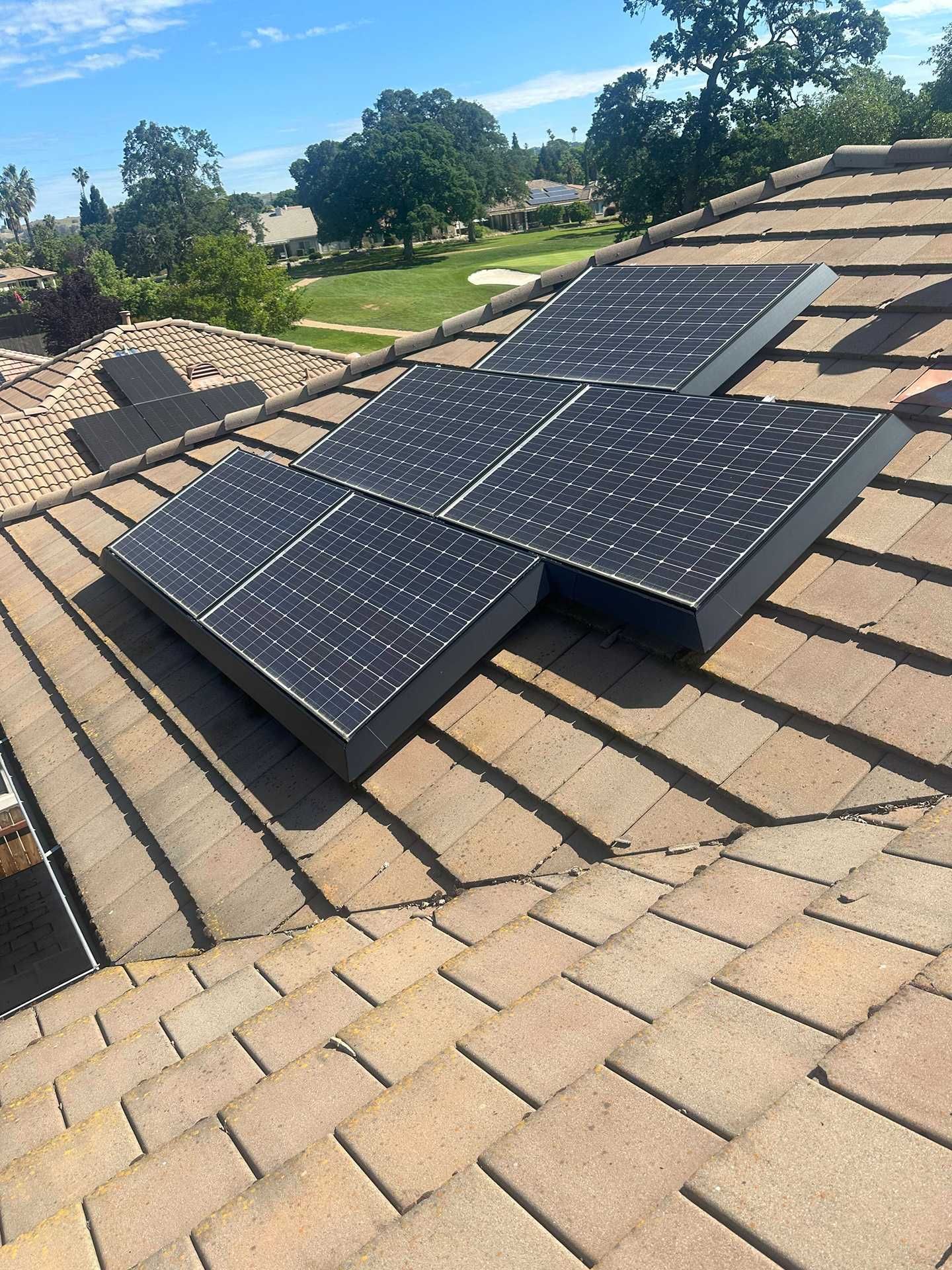 Solar panels mounted on a shingled roof under a clear blue sky.