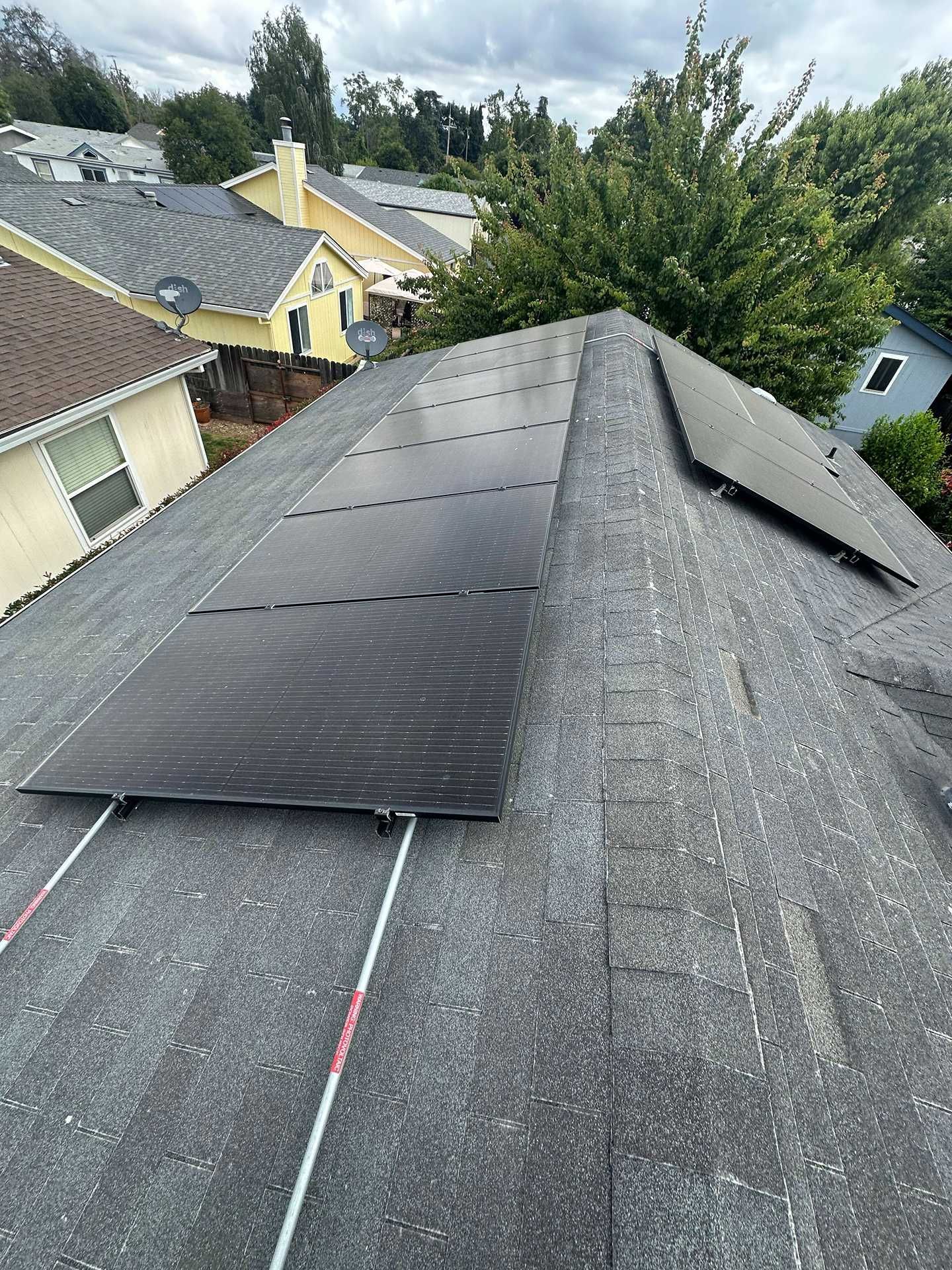 Roof with installed solar panels on a residential house, viewed from above under cloudy skies